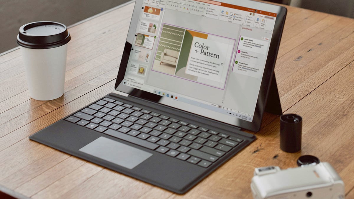 a person using a chromebook next to a paper coffee mug