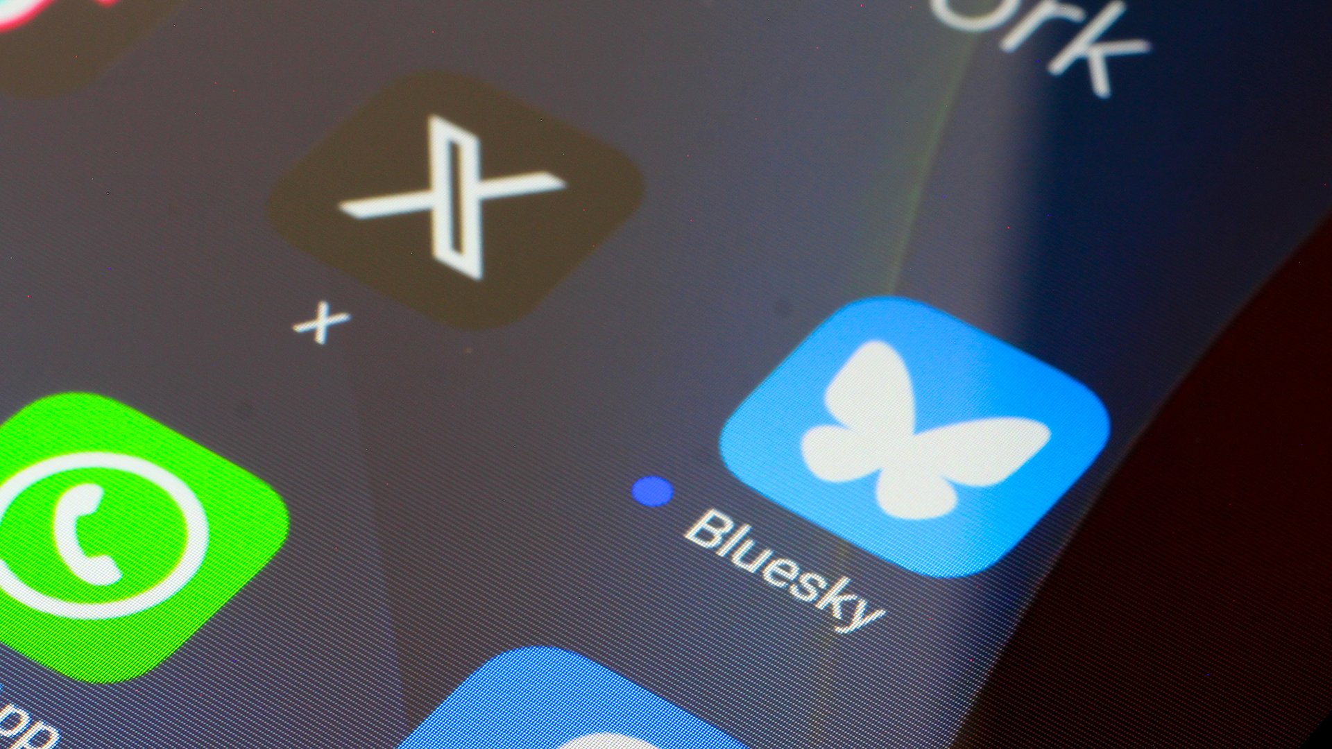 A close-up of a smartphone screen shows the X and Twitter logos.