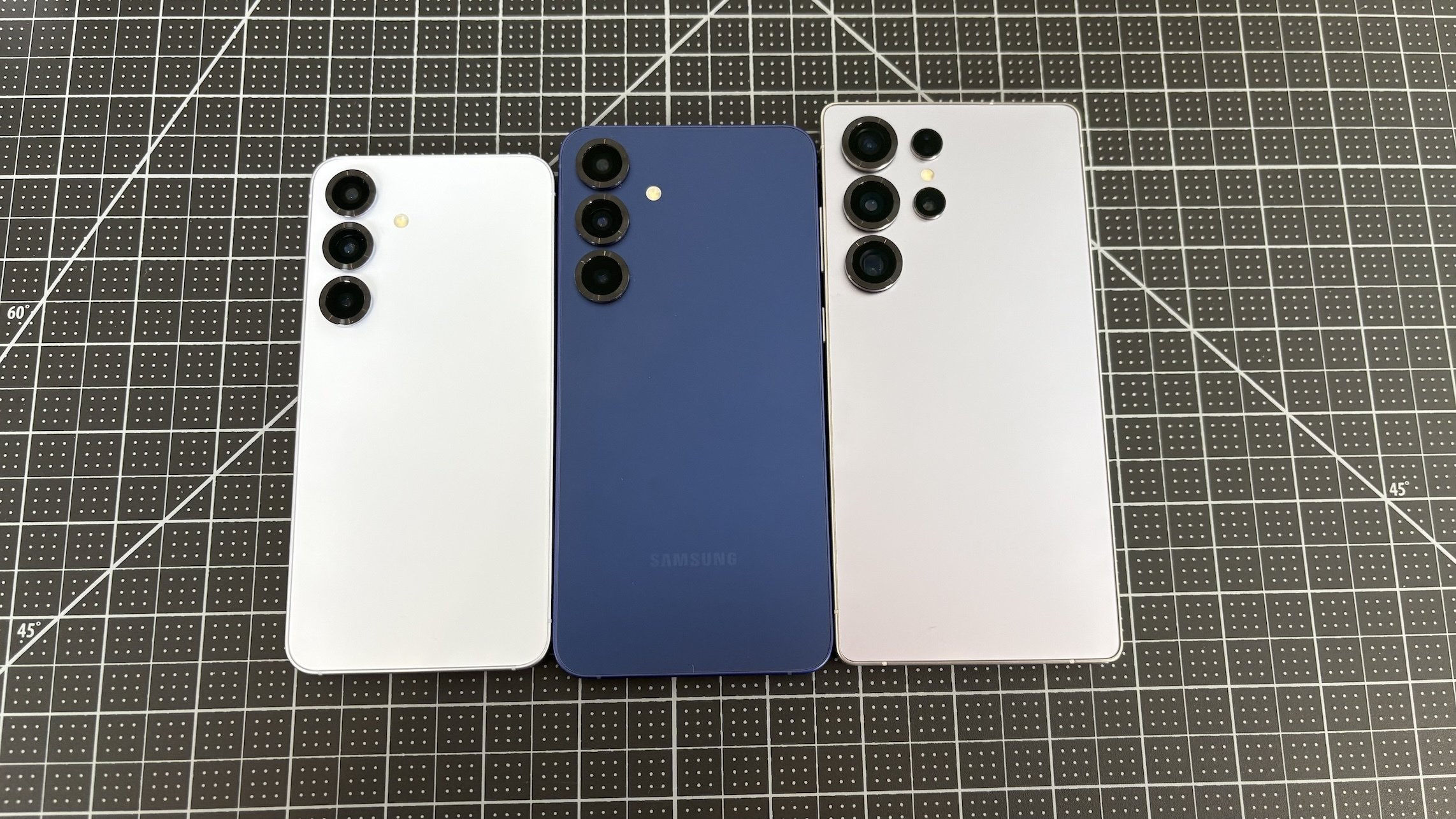 Samsung Galaxy S25, S25 Plus, and S25 Ultra lined up next to each other against a black background