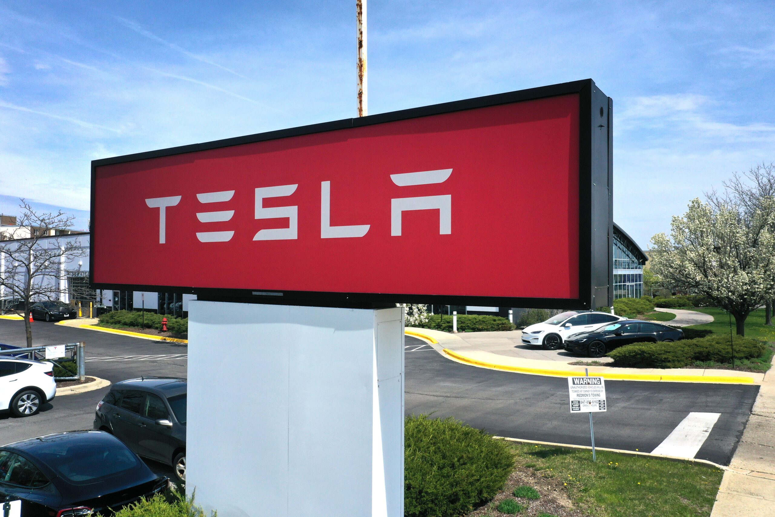 A sign marks the location of a Tesla dealership