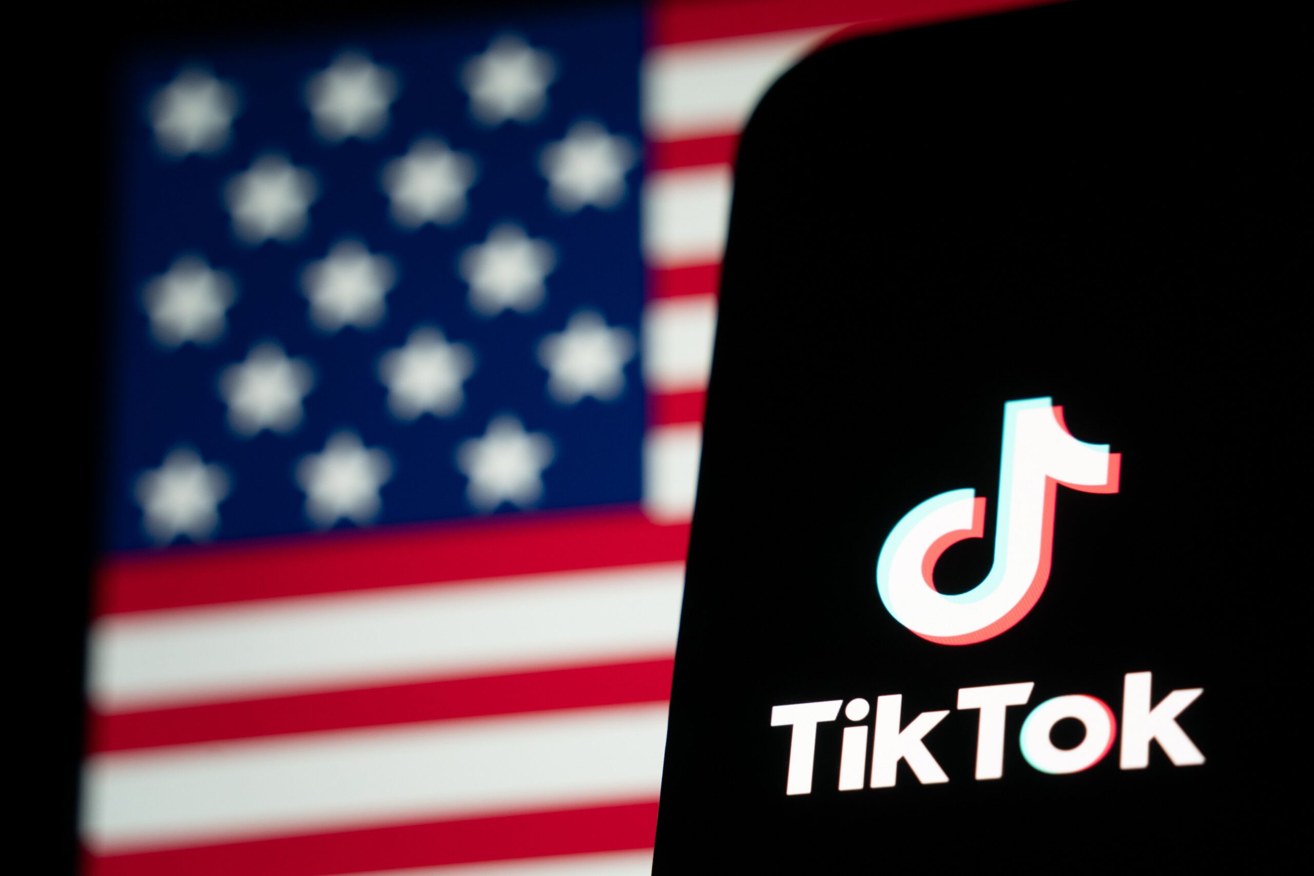 The TikTok logo and flag of the United States are seen on screens on January 18, 2025 in Hong Kong, China. As the impending TikTok ban looms, users are increasingly migrating to alternative platforms like Xiaohongshu, driven by concerns over data privacy and the potential shutdown of their favorite app. This shift reflects a broader trend where users seek platforms that offer similar engagement without the uncertainty surrounding TikTok's future in the U.S., especially as legal battles and political pressures mount ahead of the January 19 deadline for compliance or a ban.