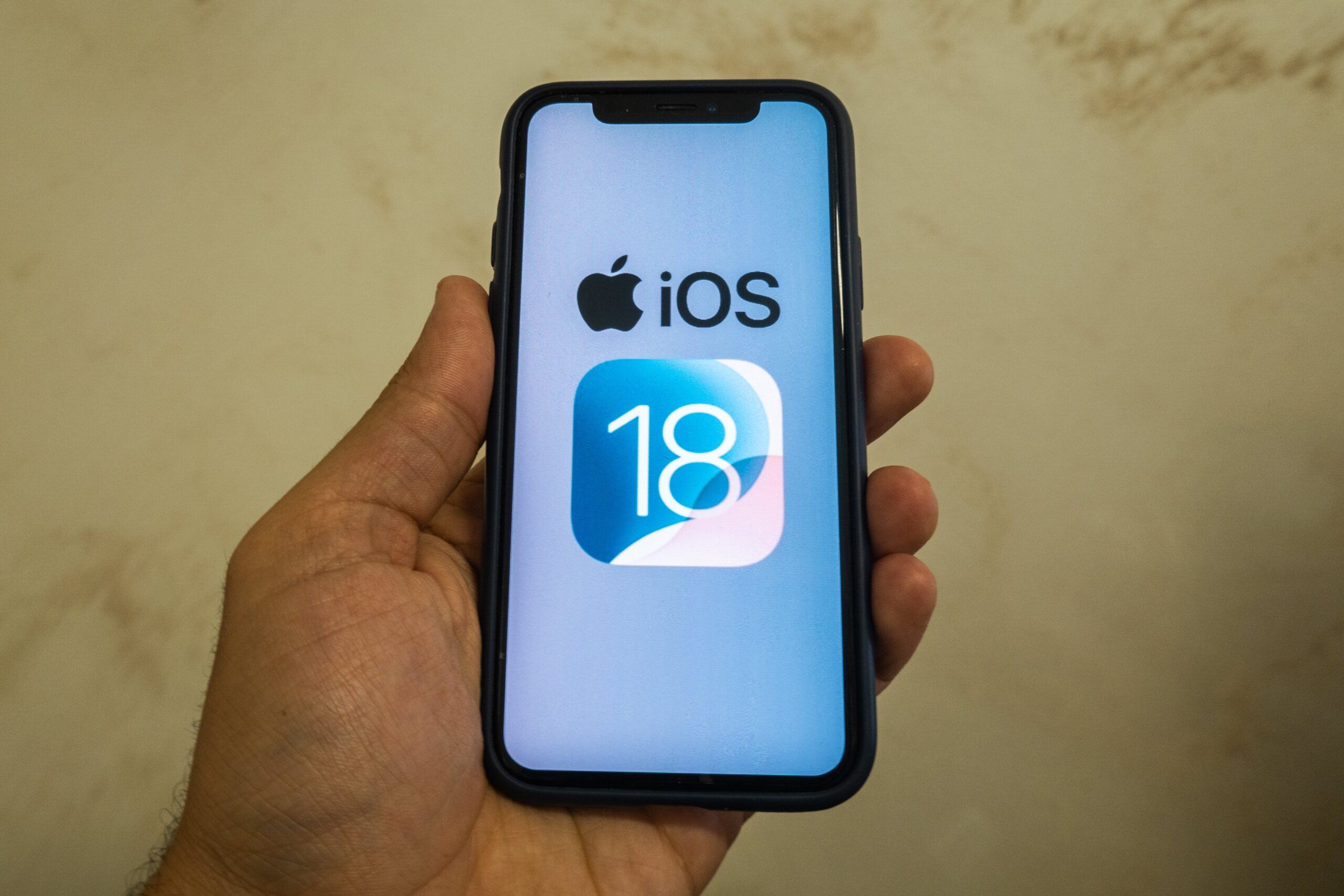 The Apple logo is seen with the iOS 18 operating system logo on a mobile device 