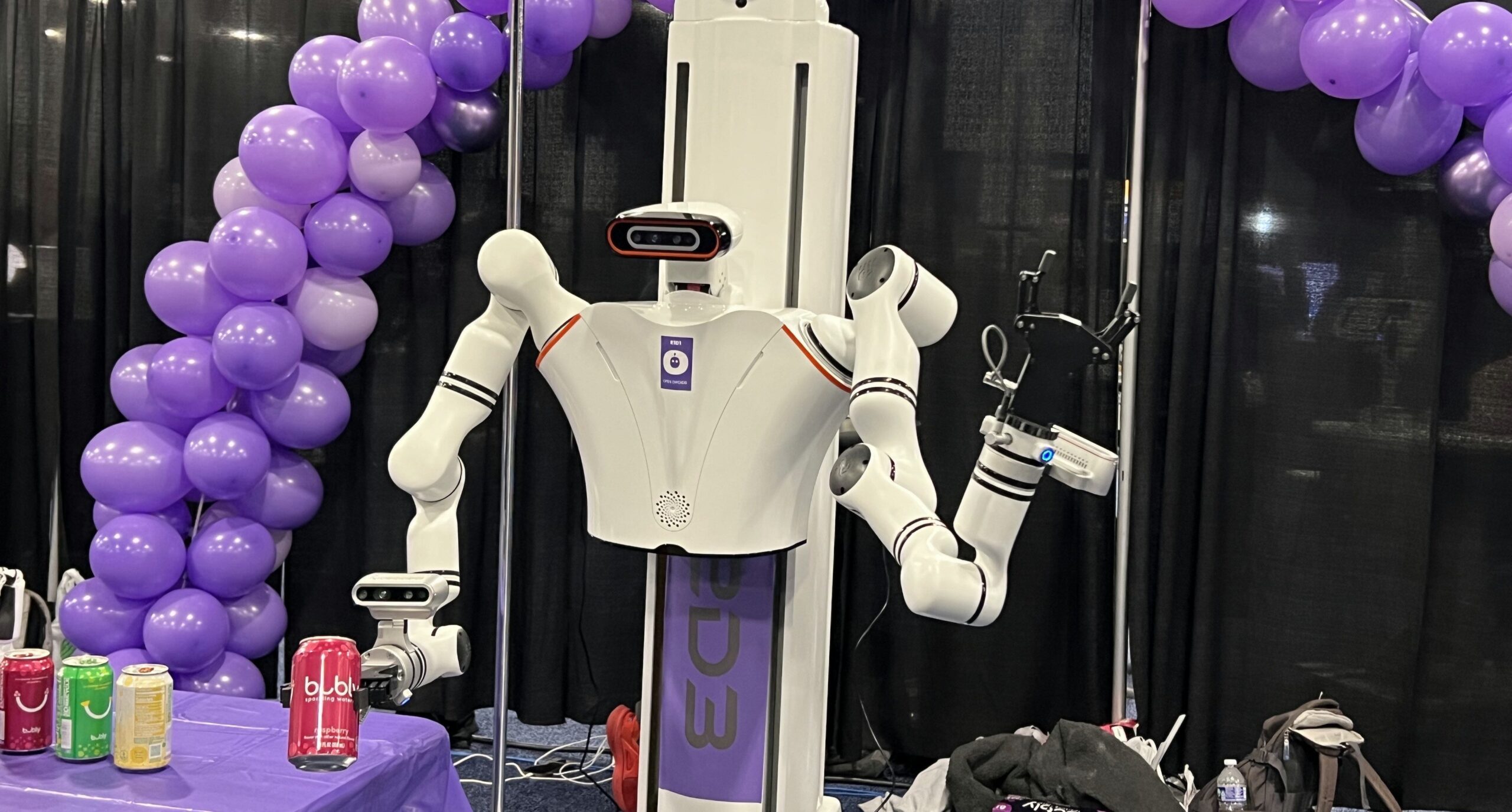 A white robot holding a can of red soda holding out to a crowd