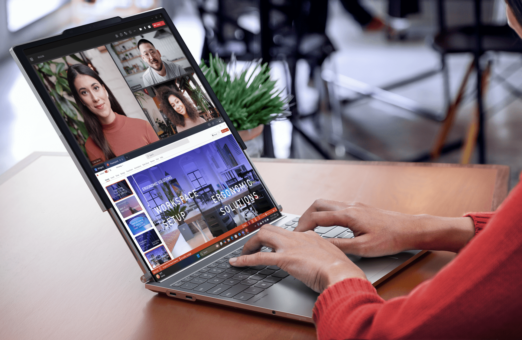 A person types on a laptop. It's screen is extended by a second screen that has been pulled out from the top of the original screen.  