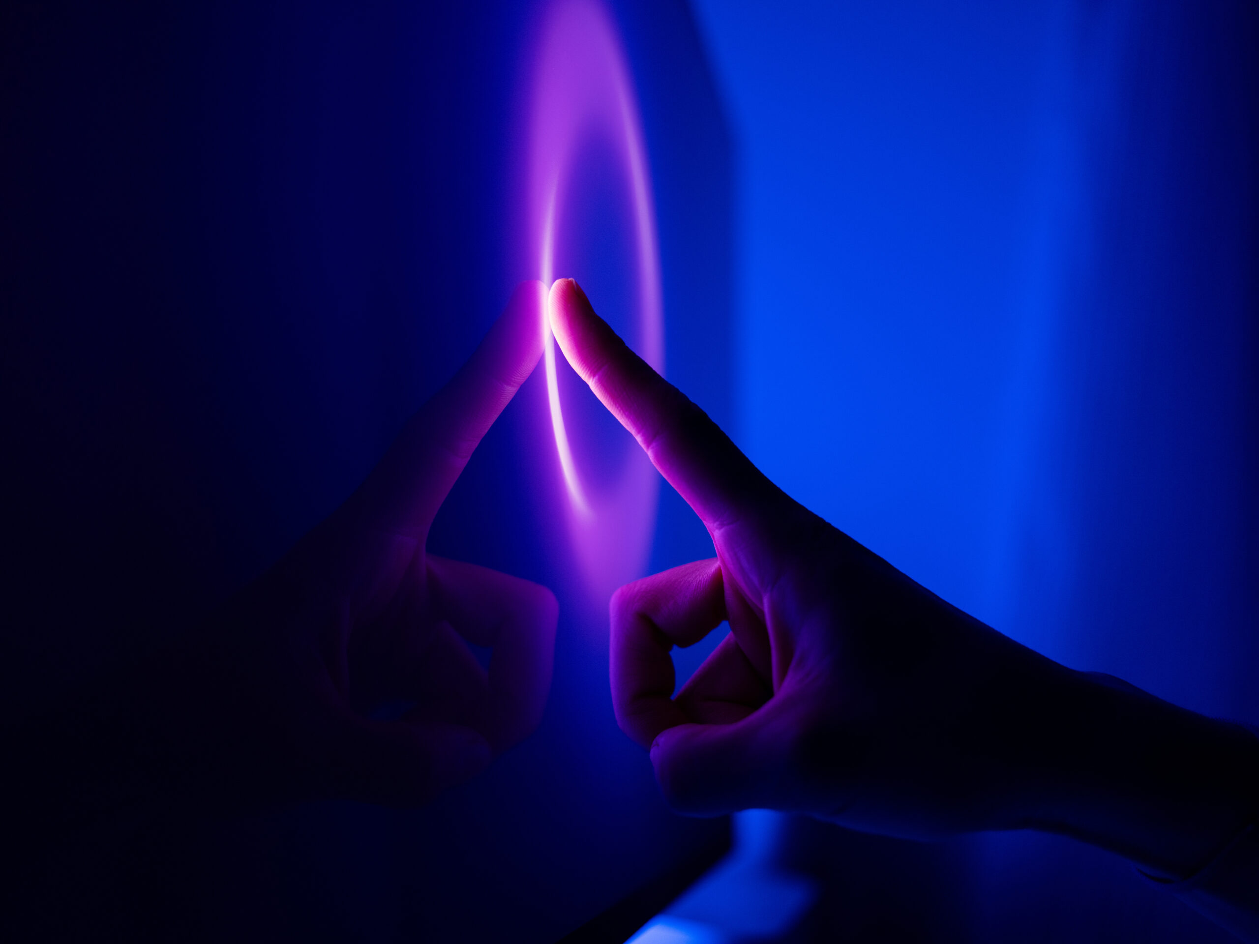 A finger taps a glowing purple and blue touch screens 