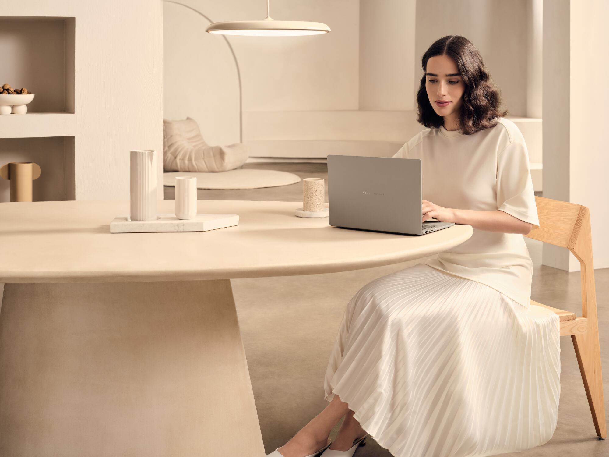 a woman typing on an asus zenbook a14 at a wood table