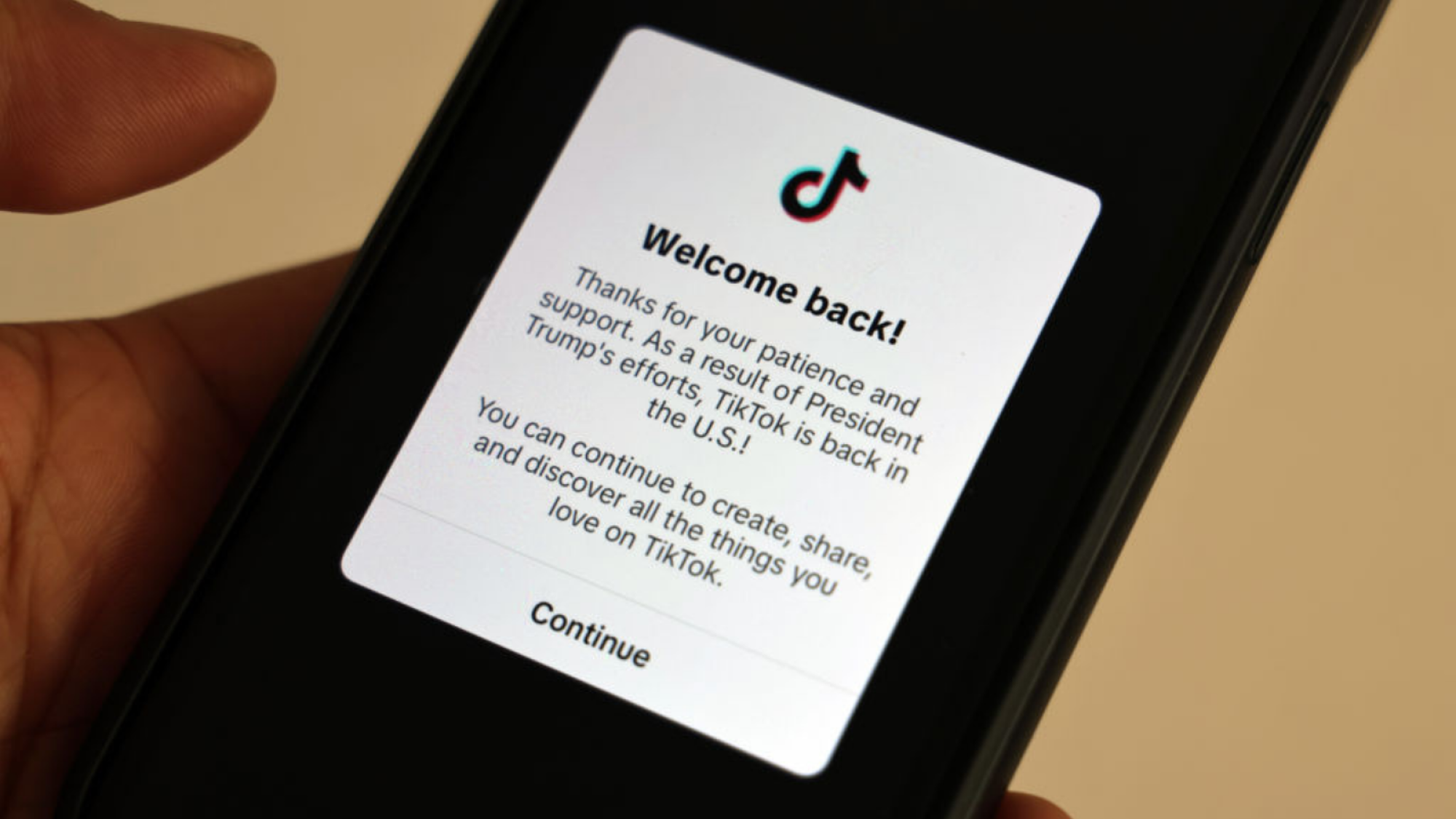 A smartphone displays a popup message on the social media platform TikTok. It reads: "Welcome back! Thanks for your patience and support. As a result of President Trump's efforts, TikTok is back in the U.S.! You can continue to create, share, and discover all the things you love on TikTok."