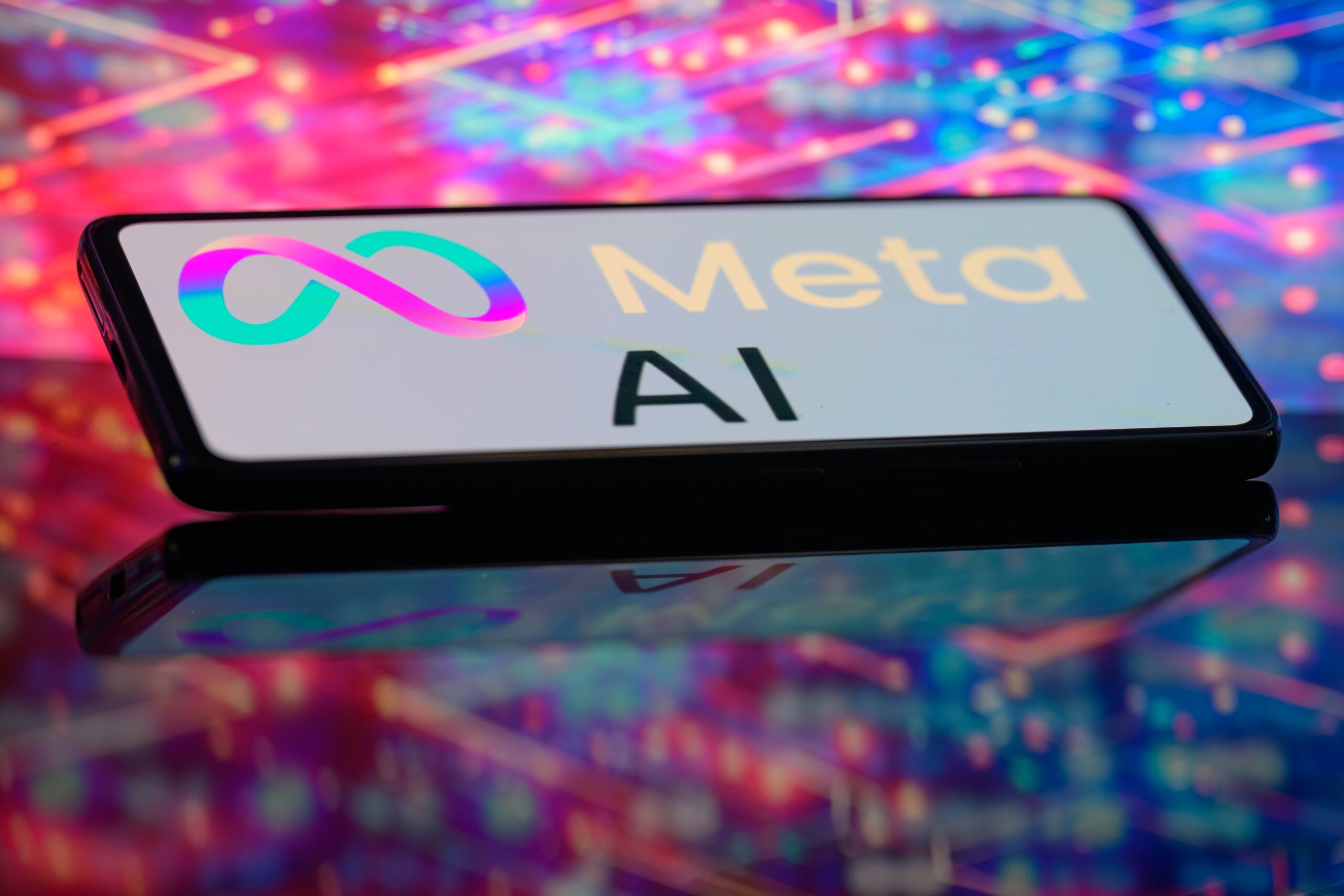 A phone displays a Meta AI logo in front of a glowing, multi-colored background.