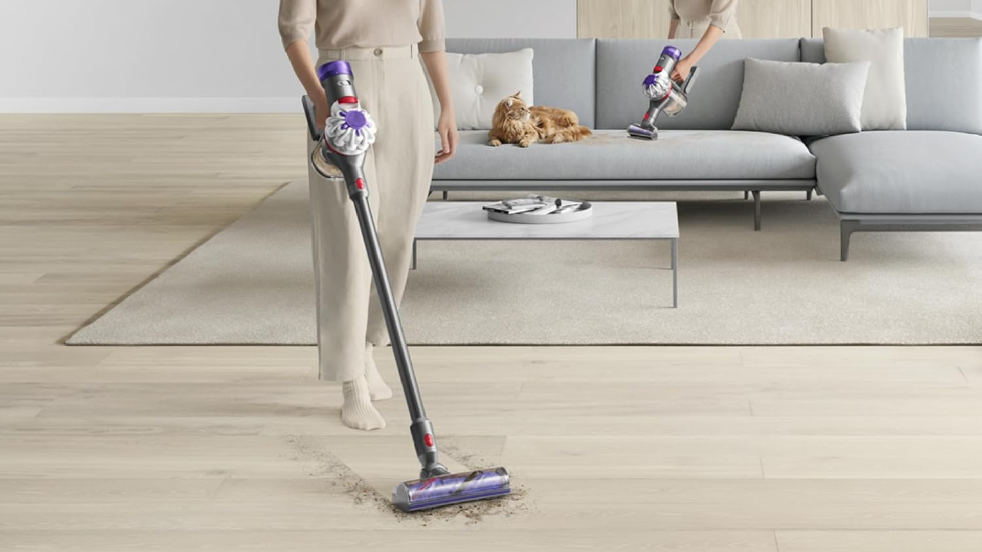 A person using a Dyson V8 to clean up dirt in a living room.