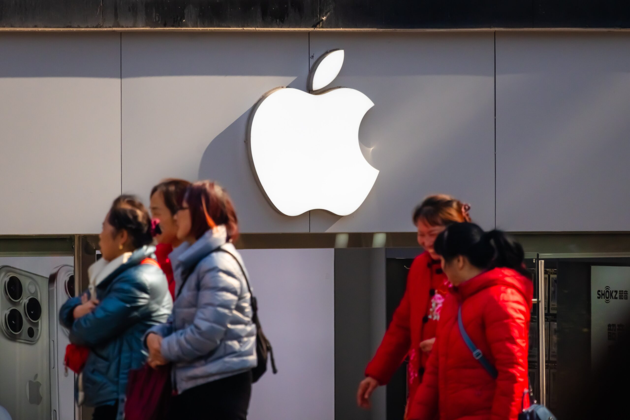 People walk past an Apple store with its iconic logo displayed on the storefront