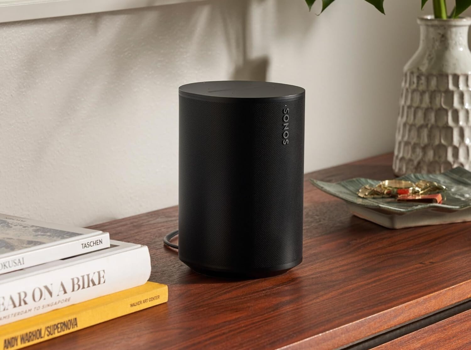 the Sonos Era 100 speaker sits on a wood table