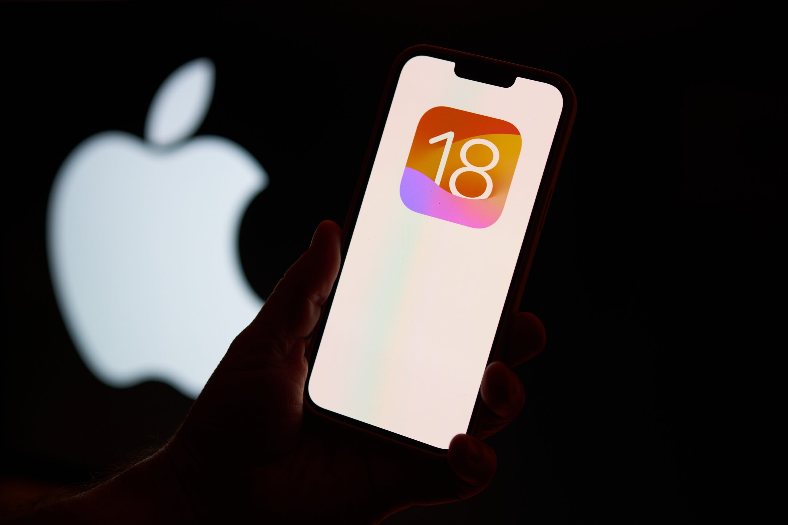 apple ios 18 logo on phone in front of apple logo