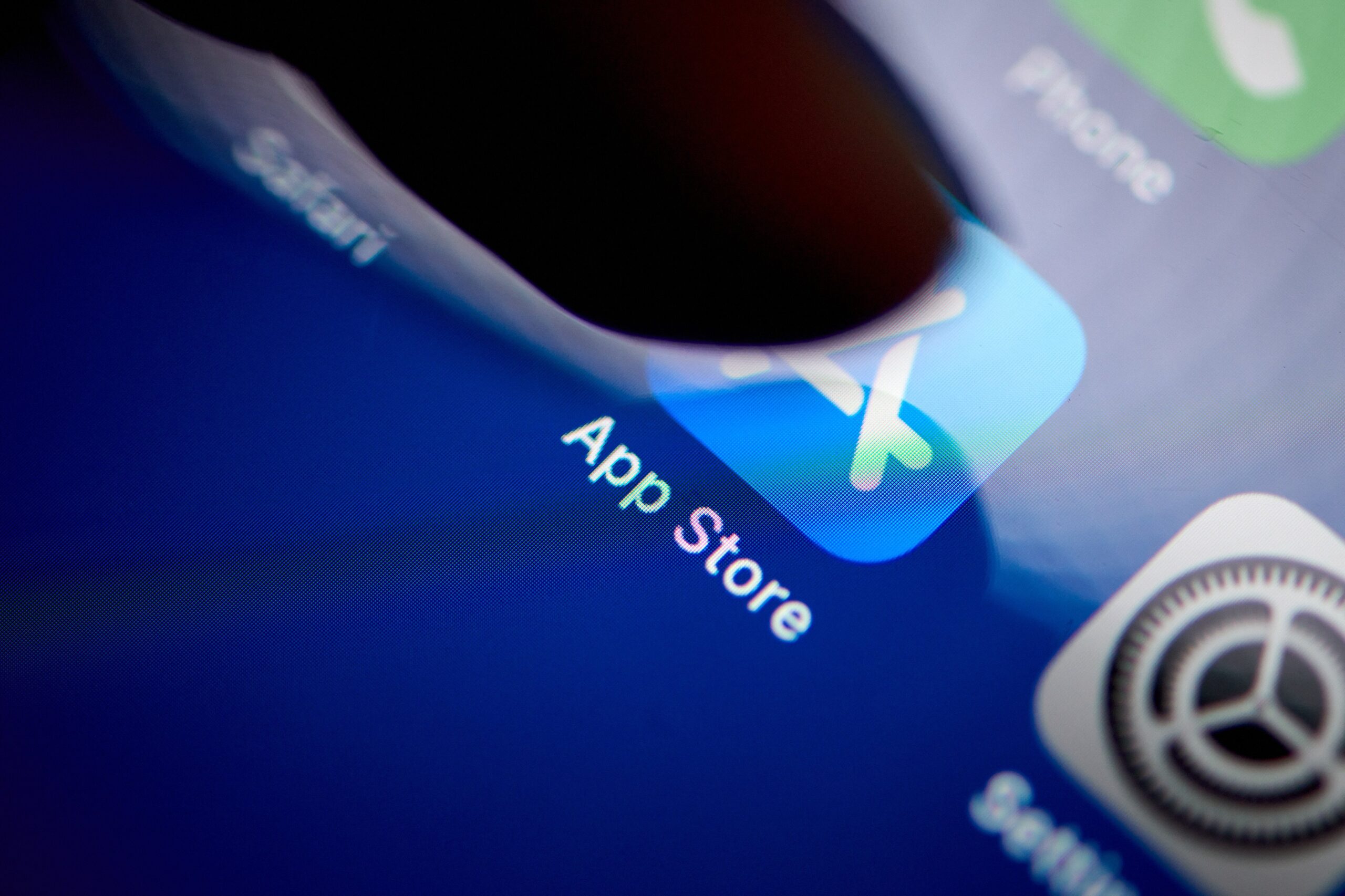 A finger taps on the Apple App Store app on a phone screen. 