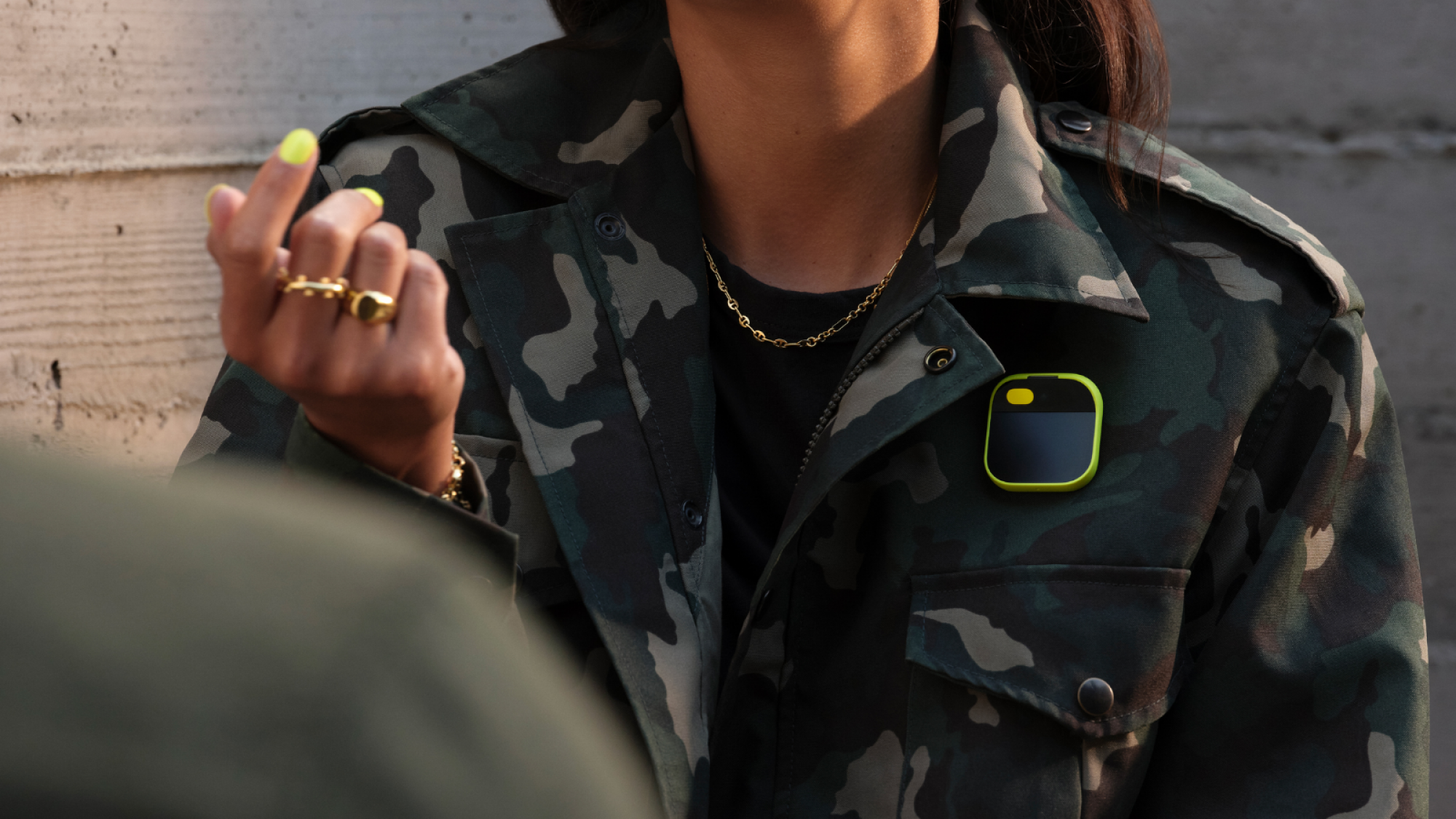 Humane's Ai Pin on someone wearing a camo jacket.