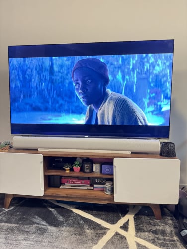 sonos arc ultra soundbar on tv stand with 'a quiet place day one' on tv