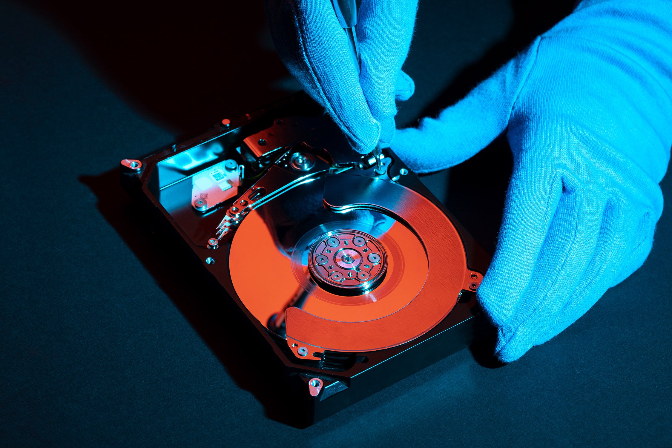 close-up of gloved hands tinkering with hard drive