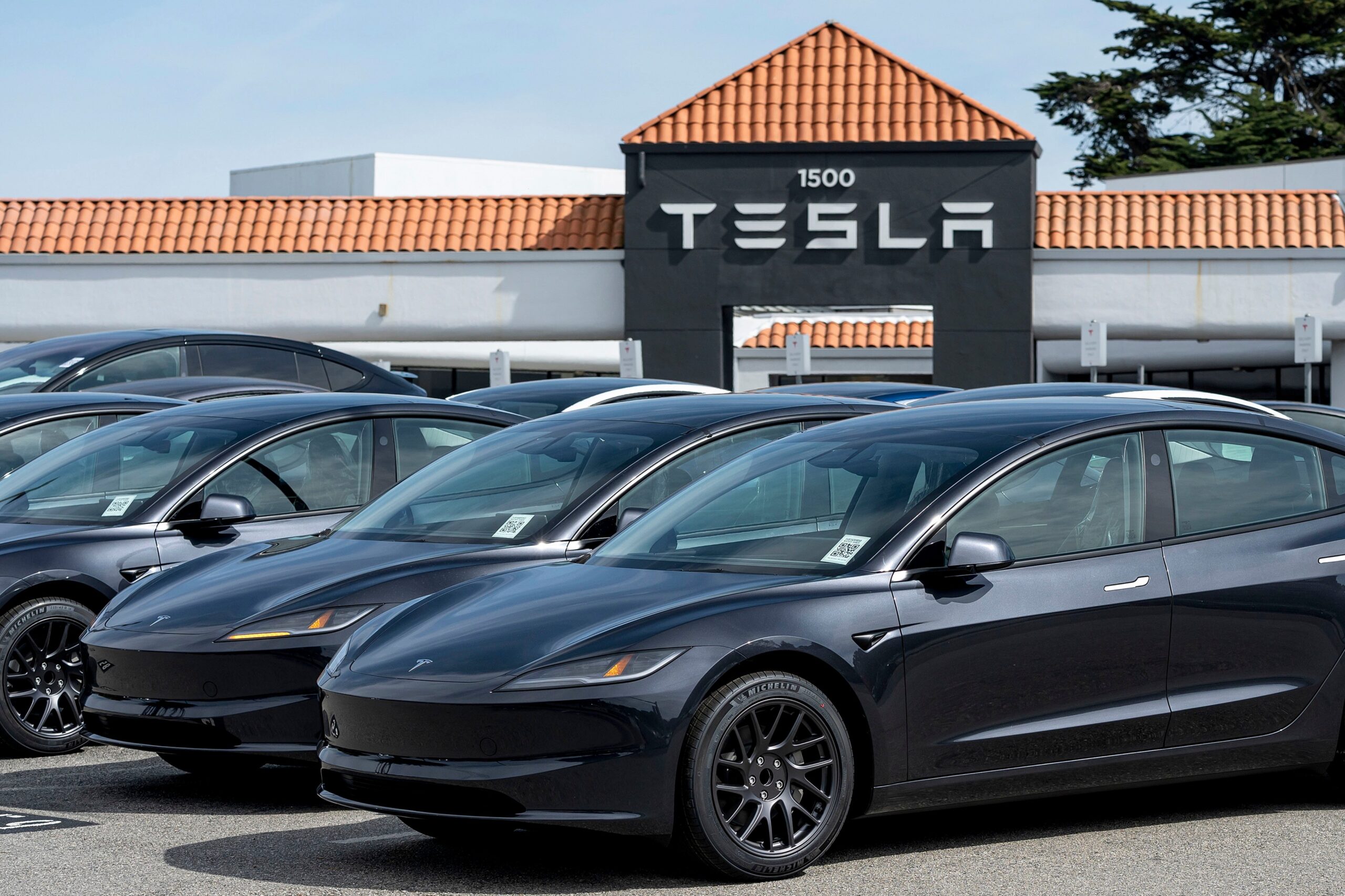 teslas in a parking lot with a tesla sign in the background