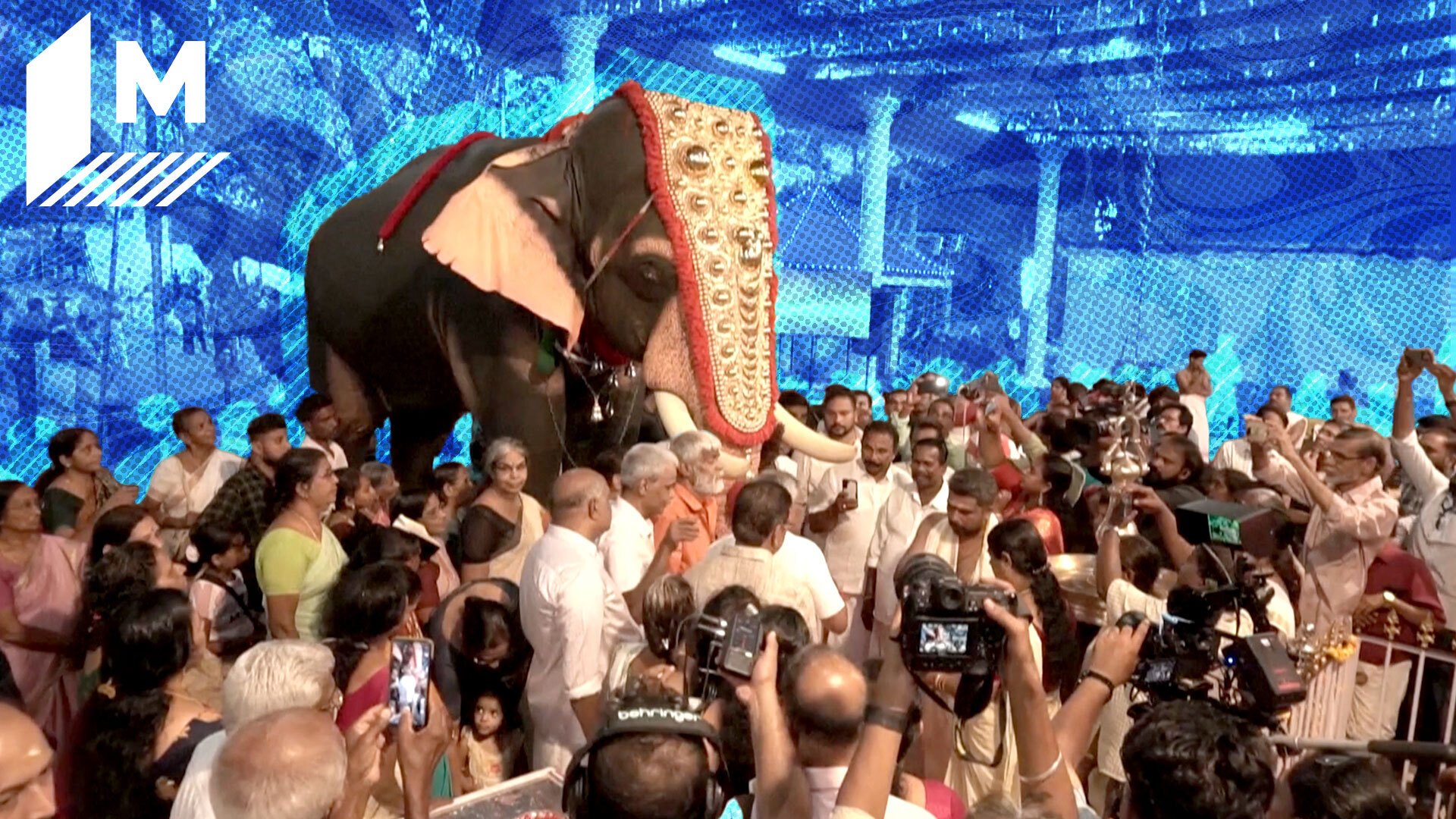 A crowd gathers around a life-size robotic elephant. The background is blurred and painted blue, with the Mashable logo hovering on the top left corner of the image