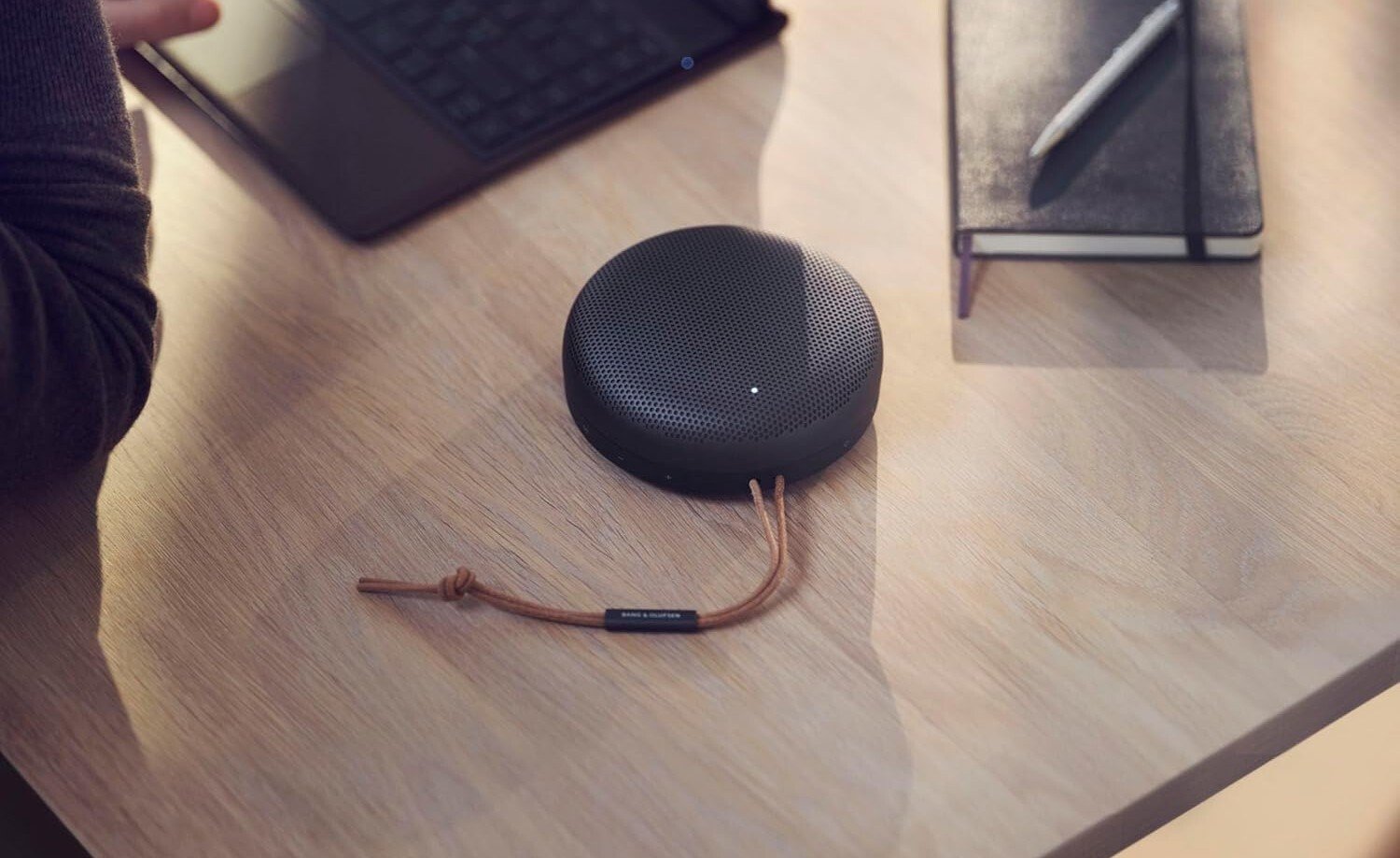 a black bang & olufsen beosound a1 speaker on a wood desk