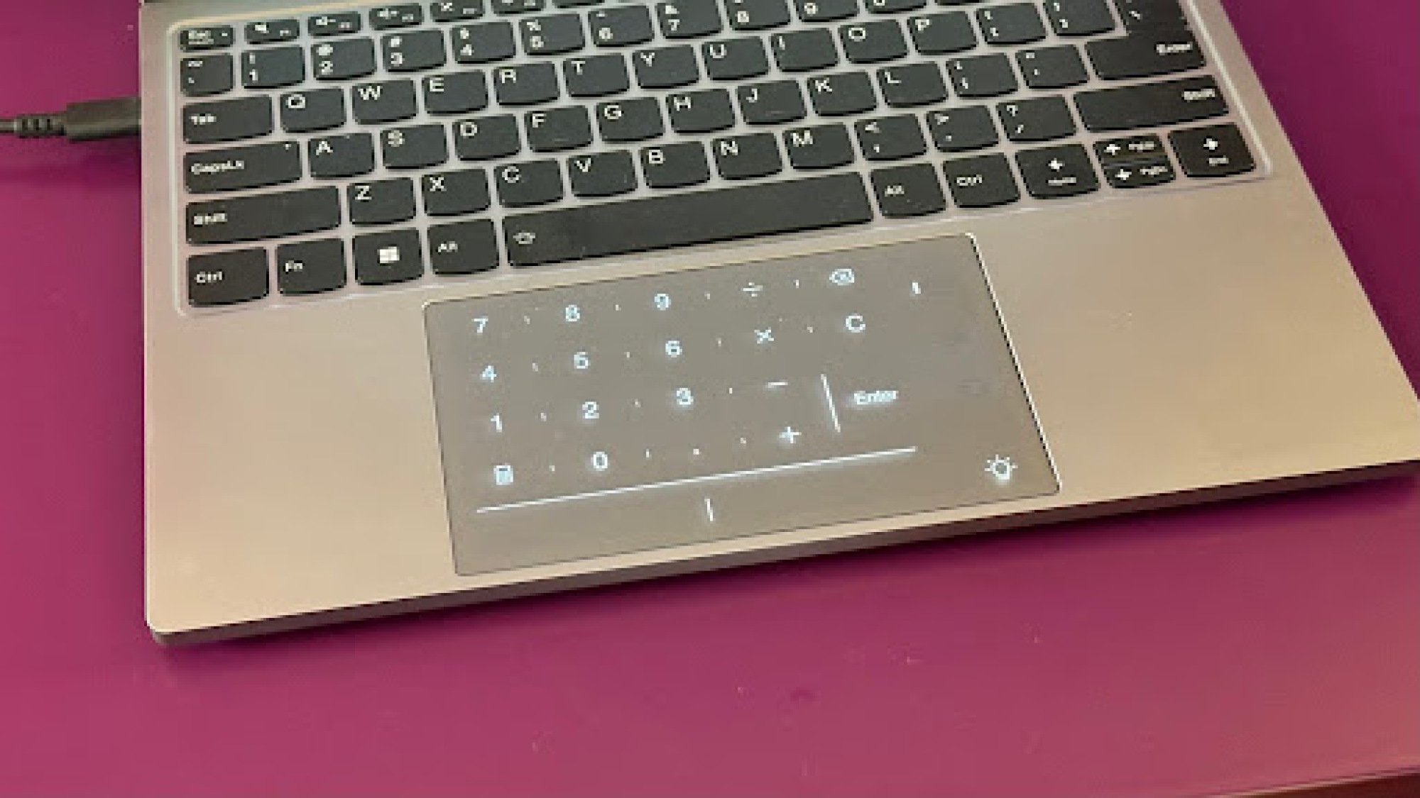 A laptop touchpad displaying a digital numeric keypad, integrated into the touch surface.