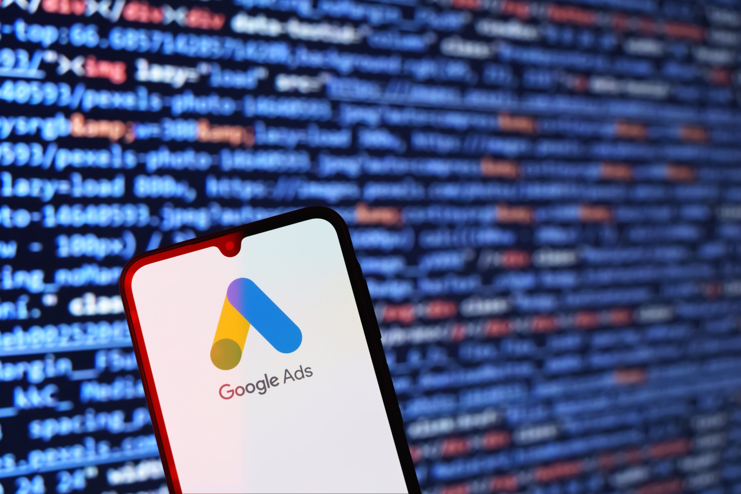 google ads logo on a smartphone in front of a screen of code