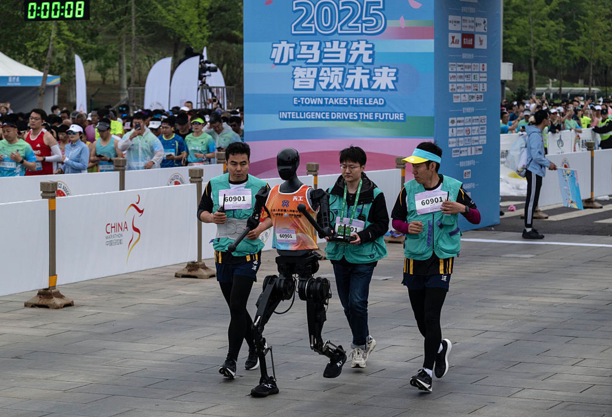 A Humanoid robot called Tiangong runs with support technicians in the Beijing E-Town Humanoid Robot Half Marathon