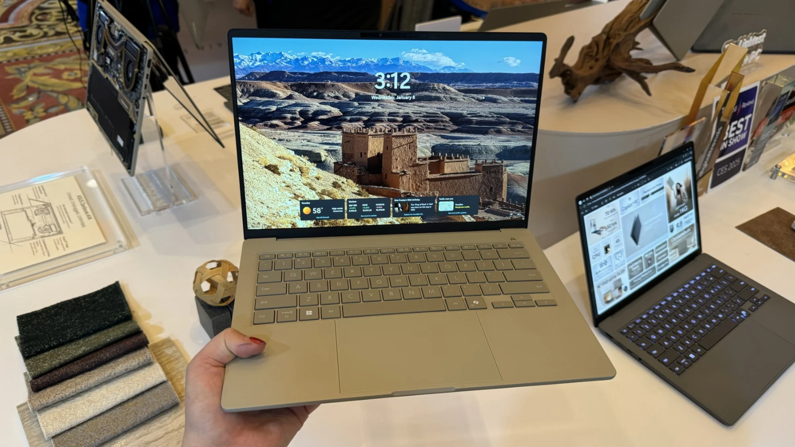 a close-up of a person holding the asus zenbook a14 with one hand at asus' ces showroom