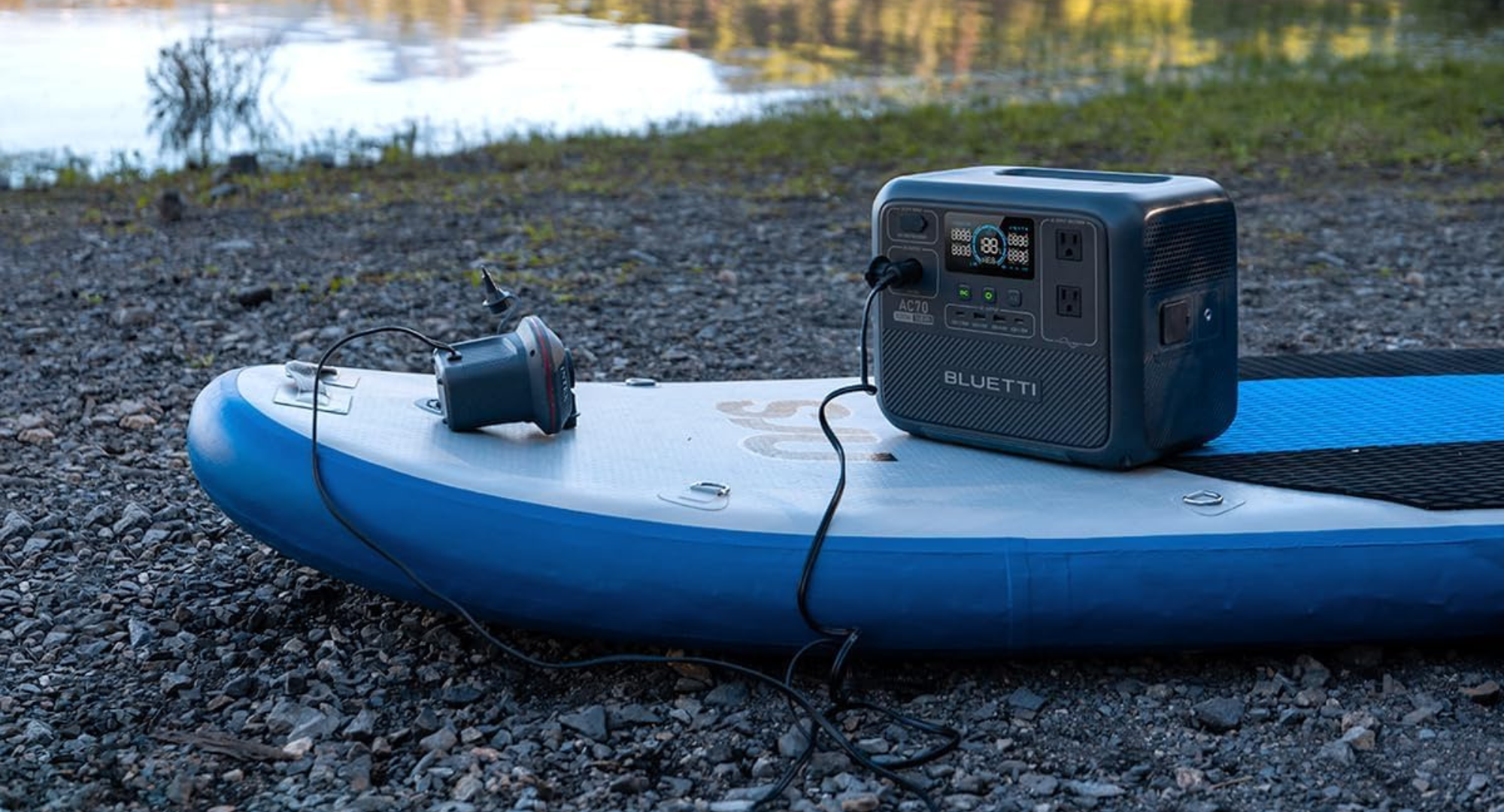A gray Bluetti AC70 portable solar generator sits on a stand-up paddleboard.