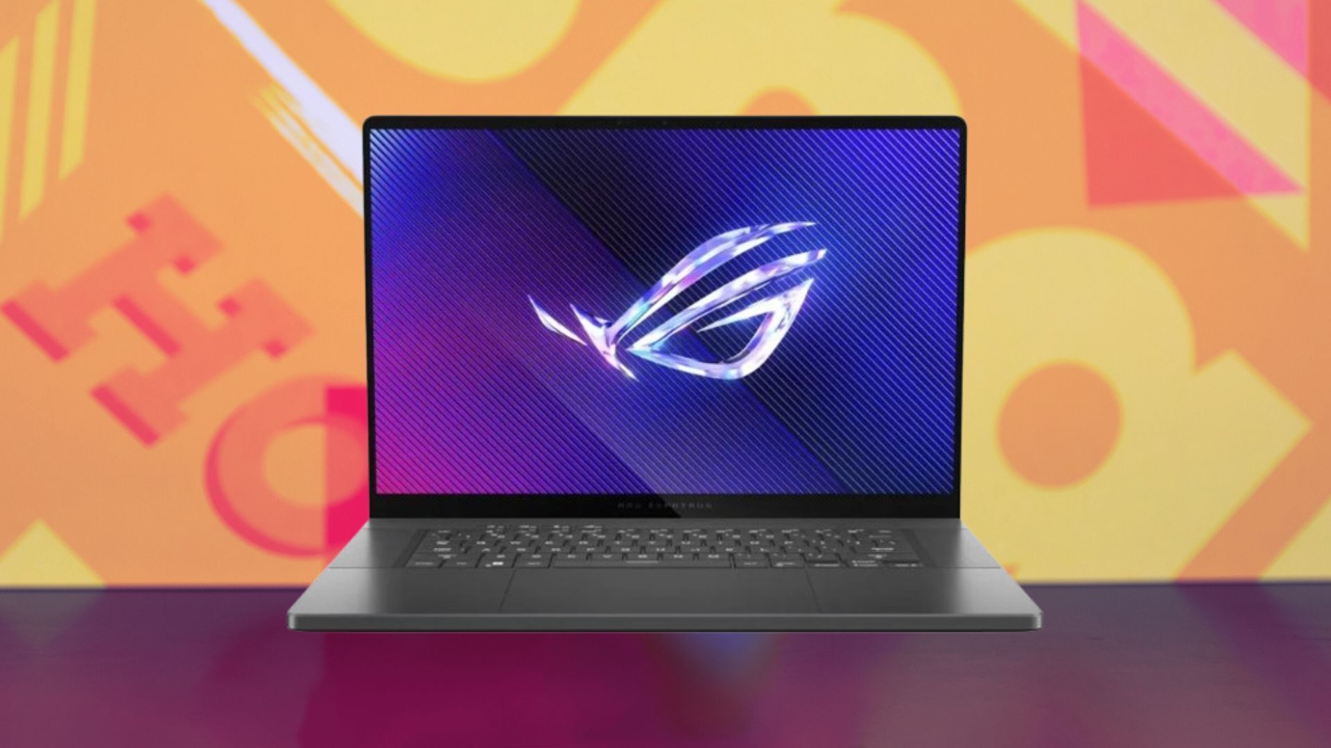 The Asus ROG Zephyrus G16 laptop appears on a multicolored abstract background.