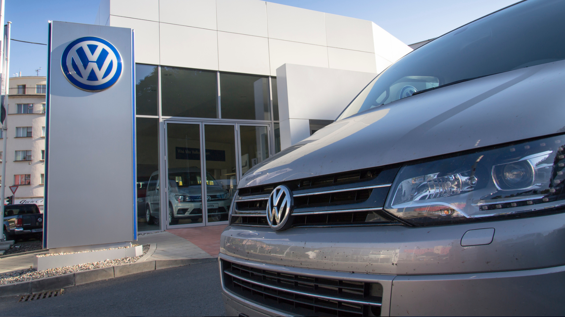 Car with Volkswagen logo in front of dealership building.