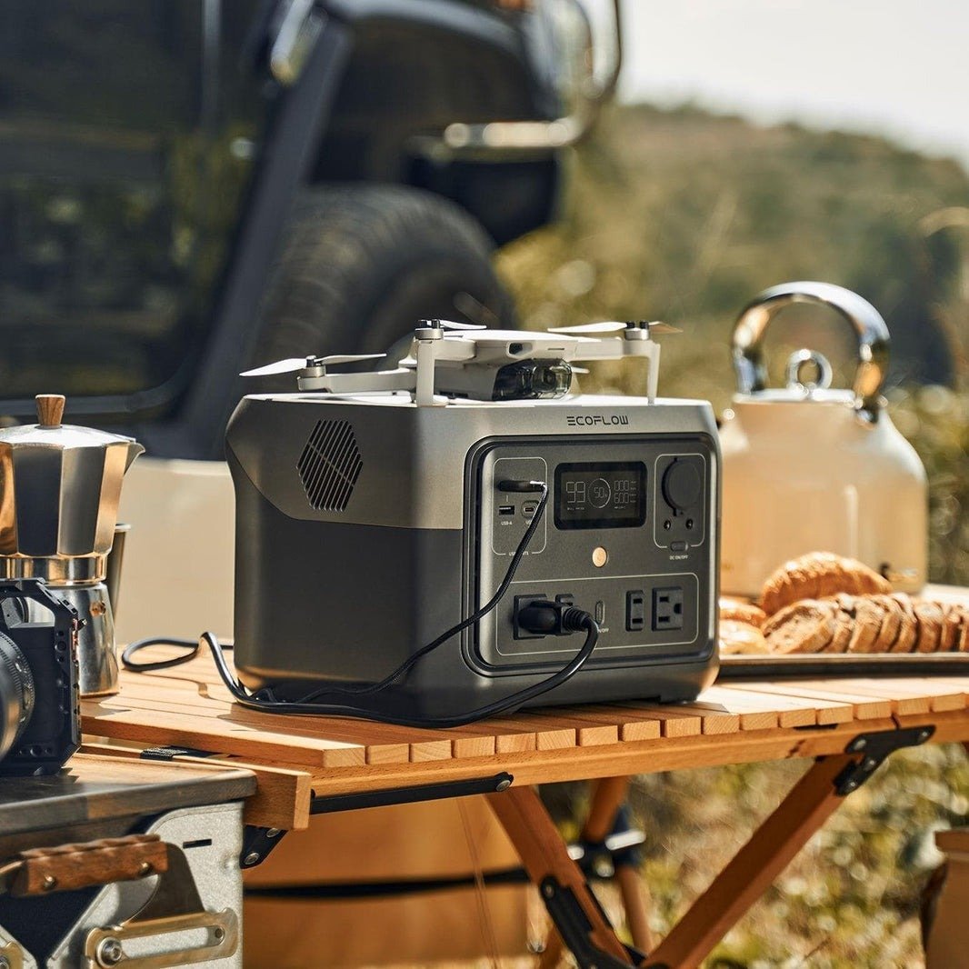 the ecoflow river 2 max portable power station on a table in the woods with camping supplies around it