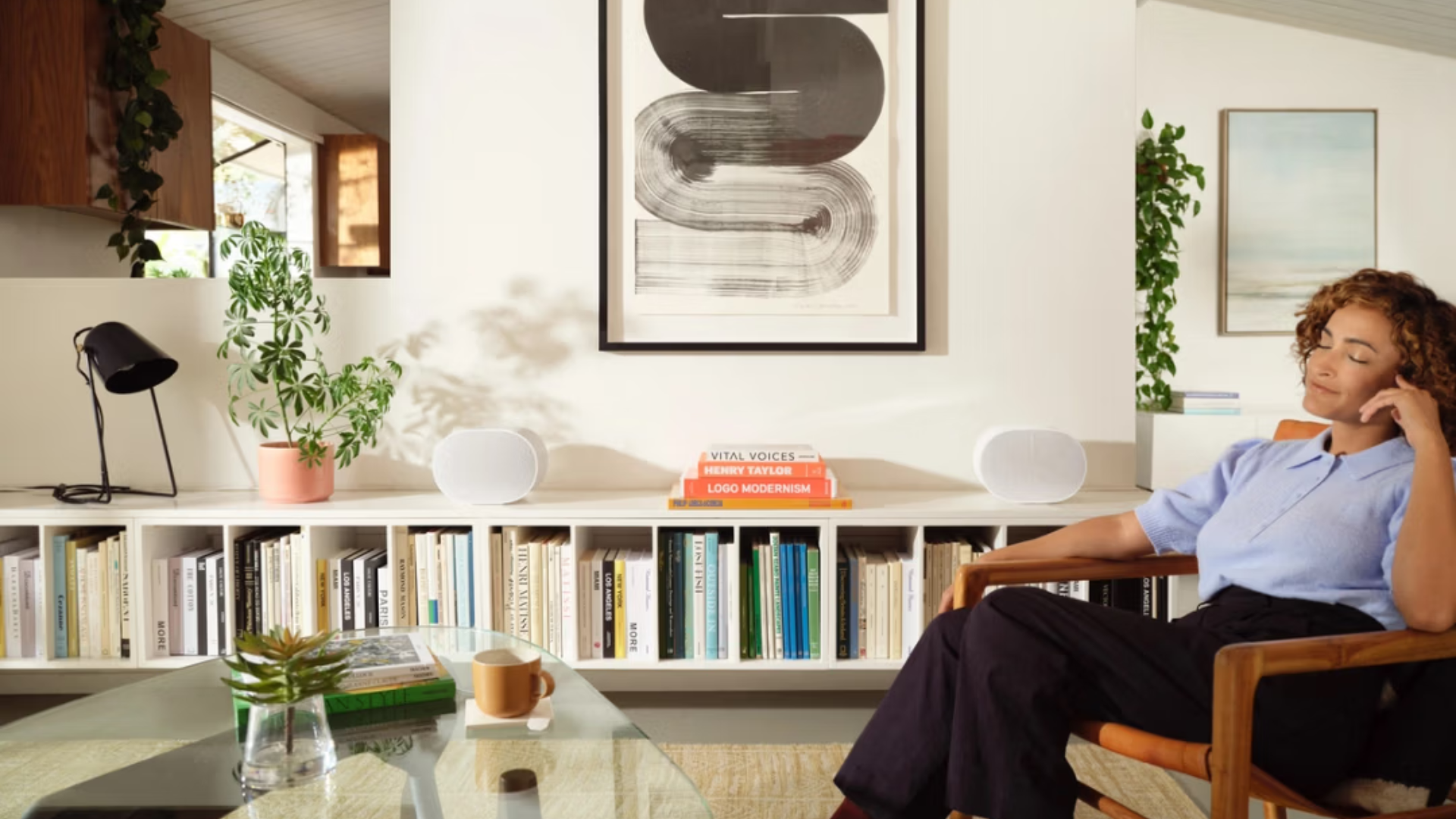 woman sitting in living room listening to records through sonos era 300 speakers