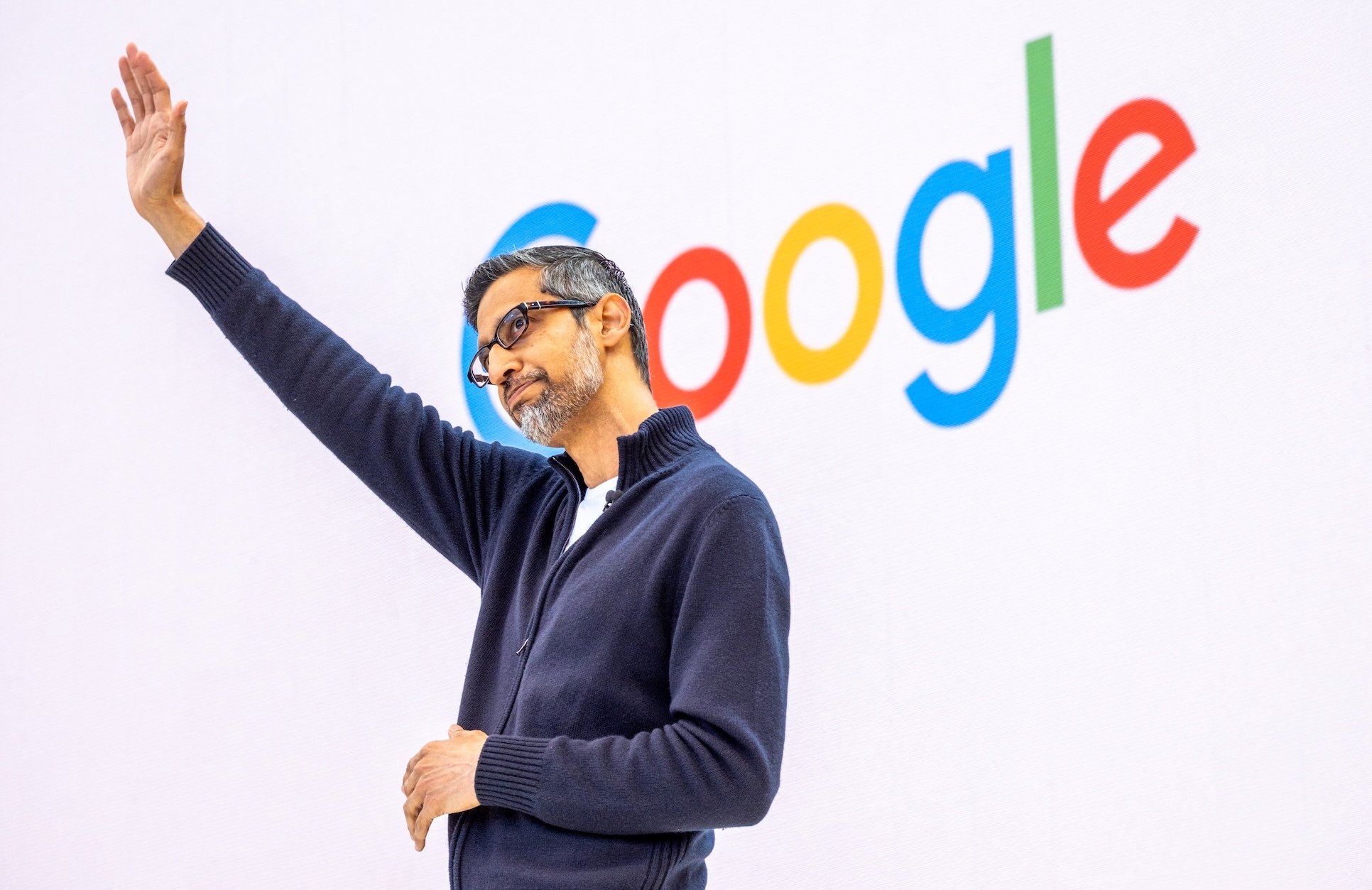 Sundar Pichai acknowledges the crowd in front of a Google logo