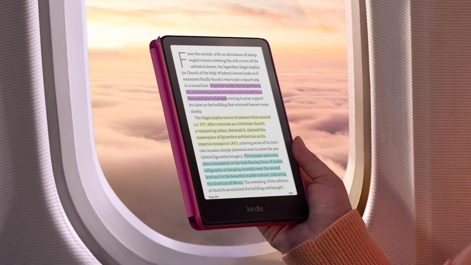 hand holding Kindle Colorsoft by window on airplane