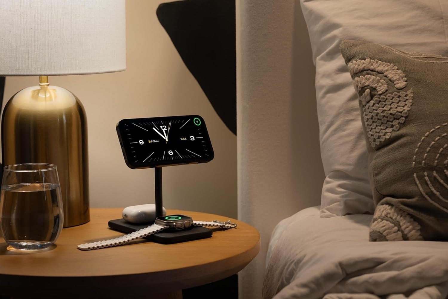 the Twelve South HiRise 3 Deluxe magsafe charger sits on a bedside table charging apple devices