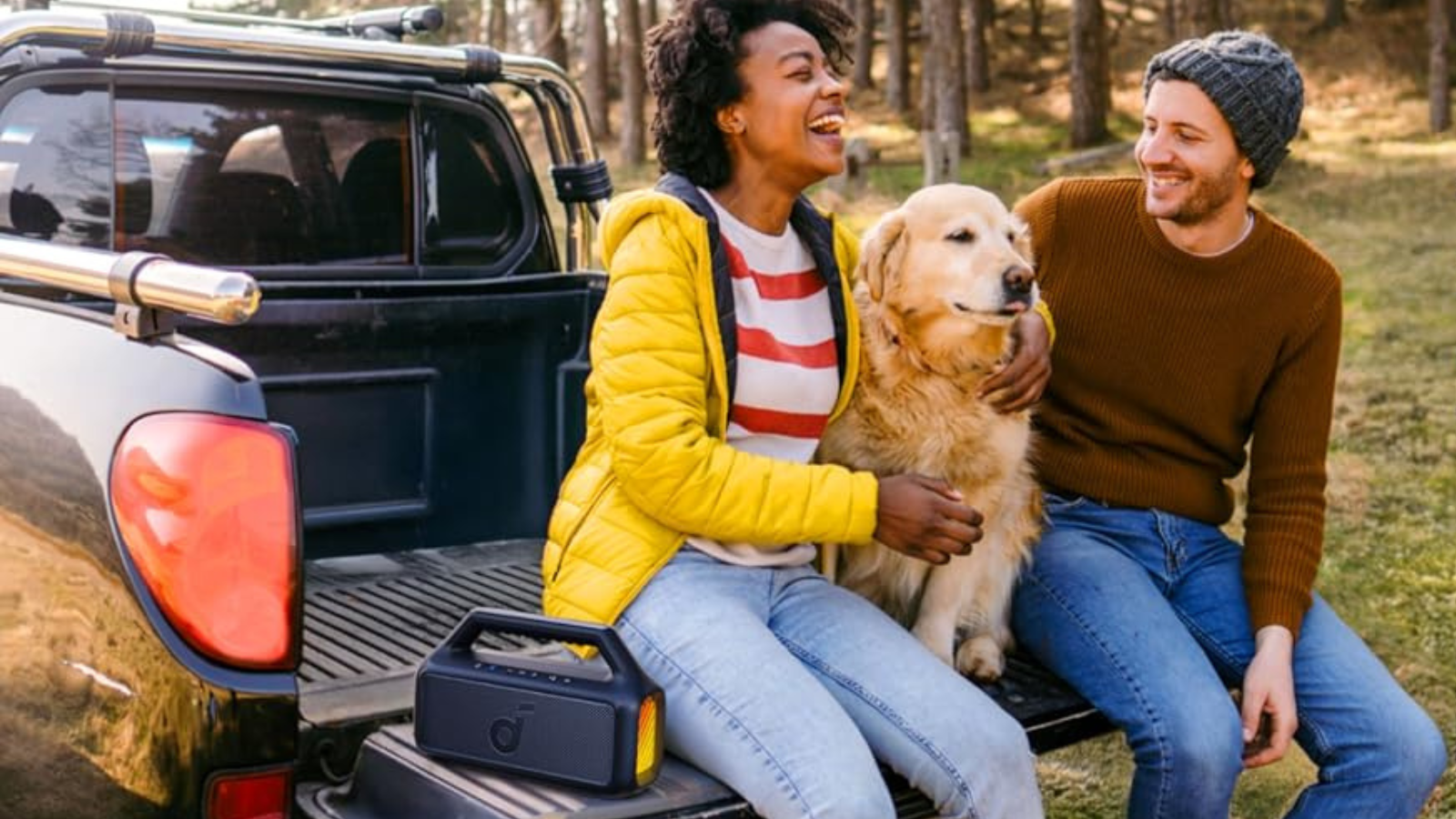 couple sitting with dog on truck tailgate and listening to Soundcore Boom 2 speaker