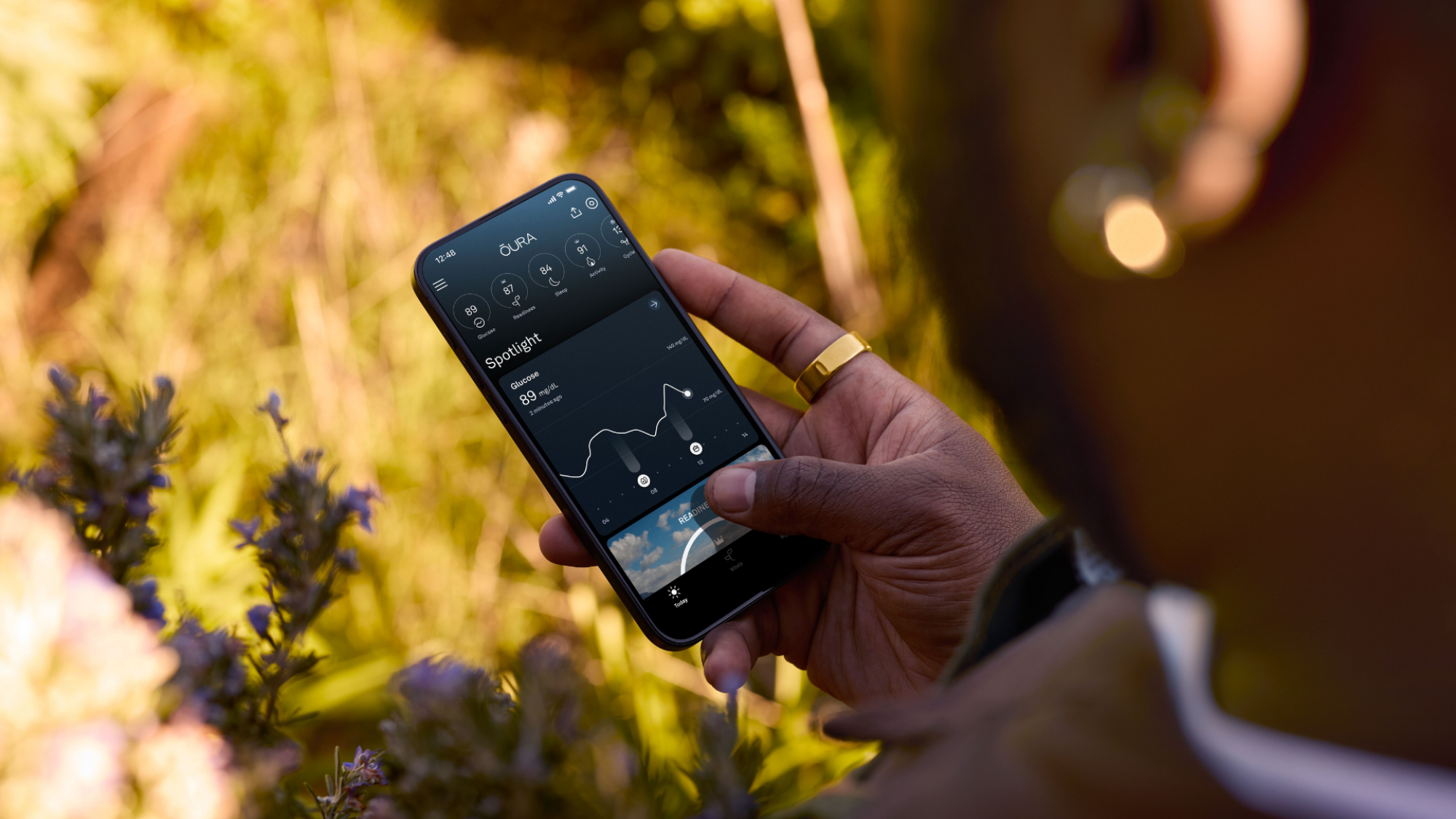 A person holding a phone showing the Oura app