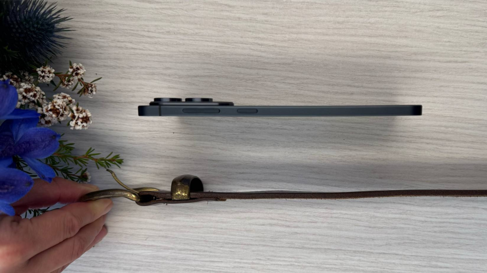 Samsung's Galaxy S25 Edge on its side, next to a leather belt also on its side. The phone is thicker than the belt, but they are comparable.