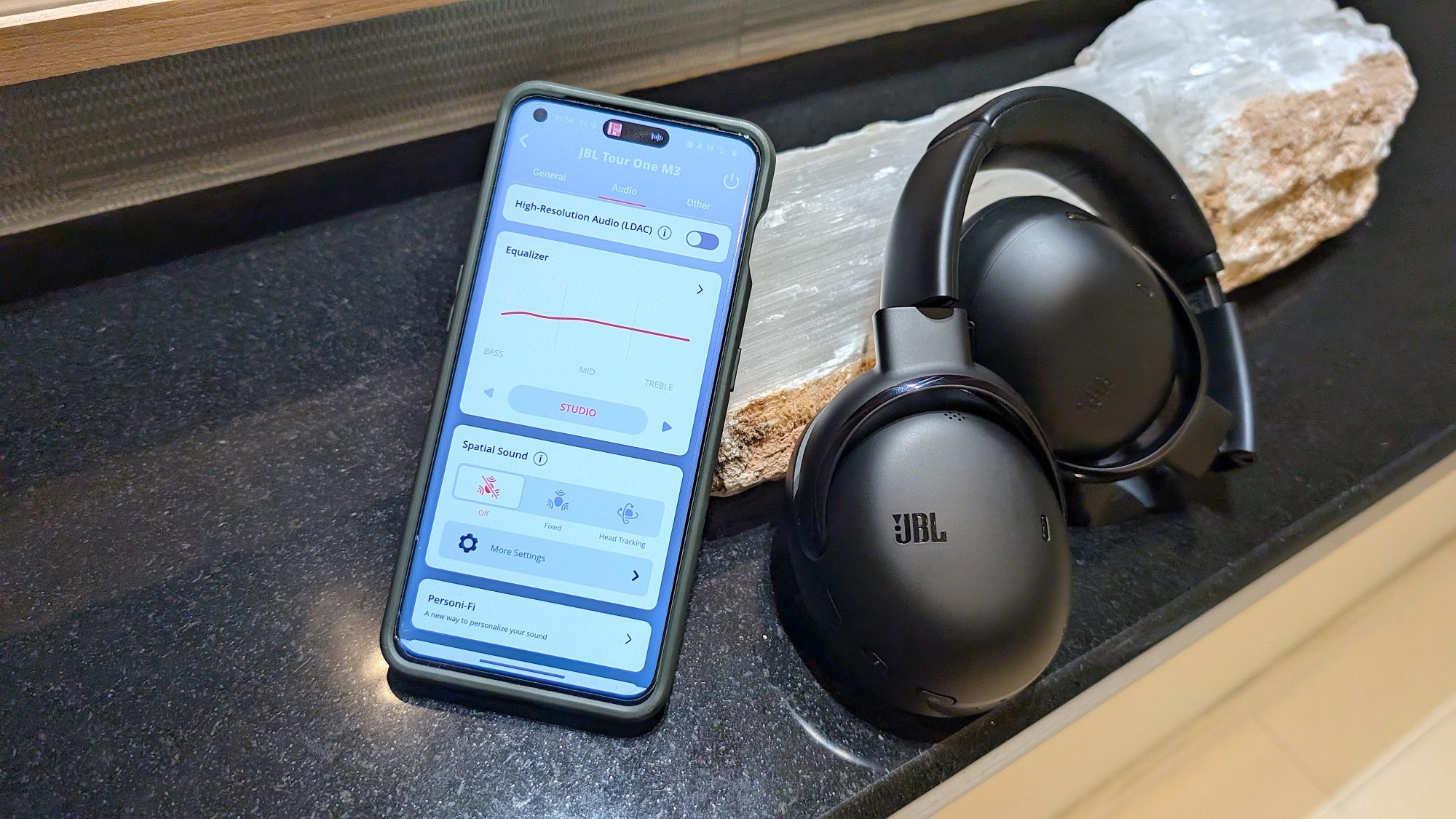 JBL headphones next to phone with JBL app open to equalizer settings
