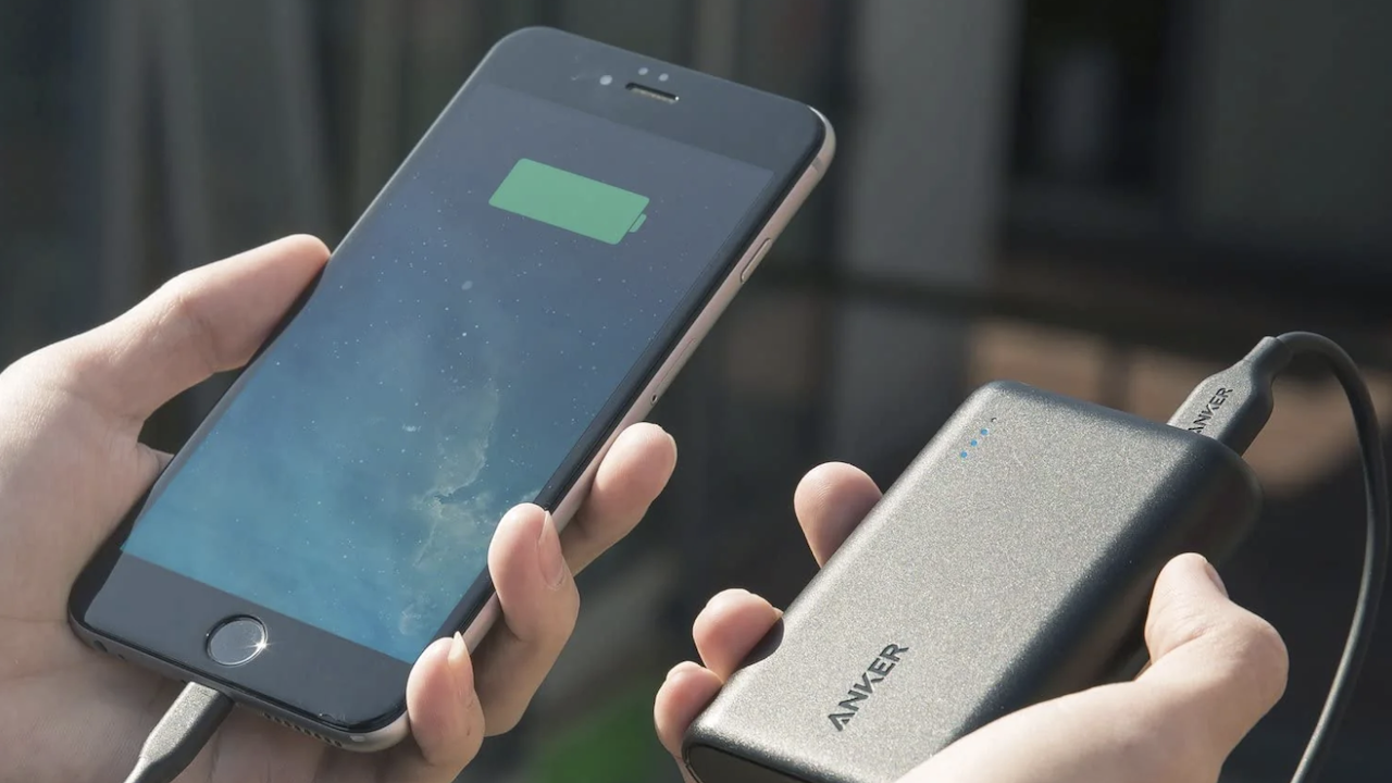 Person holding Anker power bank next to a smart phone