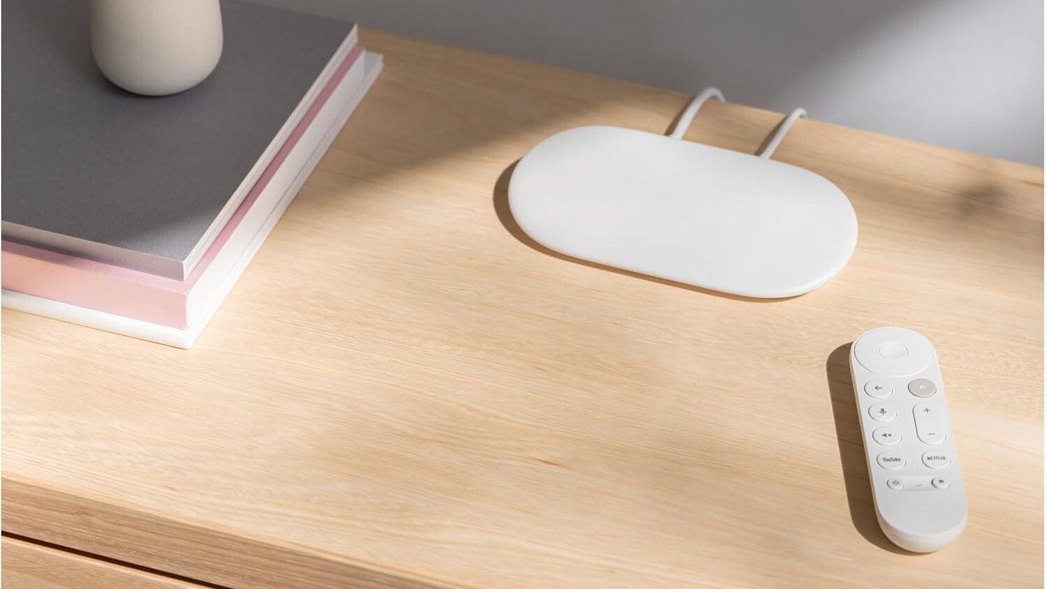 the google TV streamer and remote control sit on a light wood entertainment center