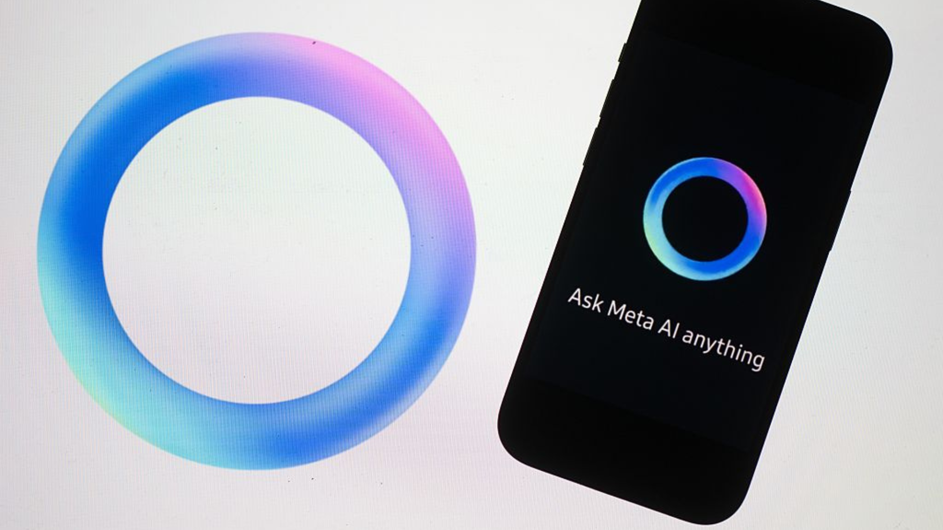 The logo of the AI software Meta AI from the Facebook group Meta is displayed on the screen of a laptop and iPhone.