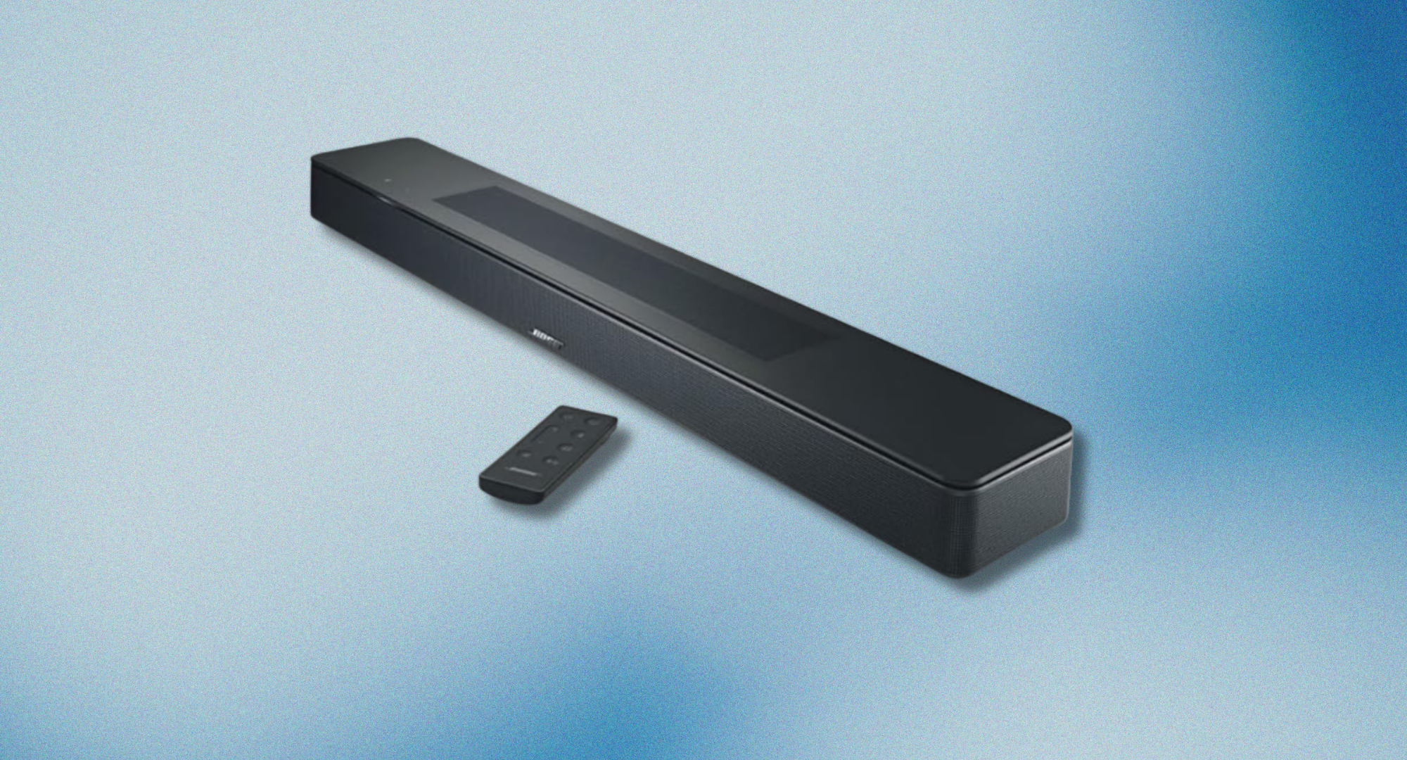 A sleek, black Bose 550 Dolby Atmos soundbar sits diagonally on a light blue background, with its small black remote control resting in front of it.