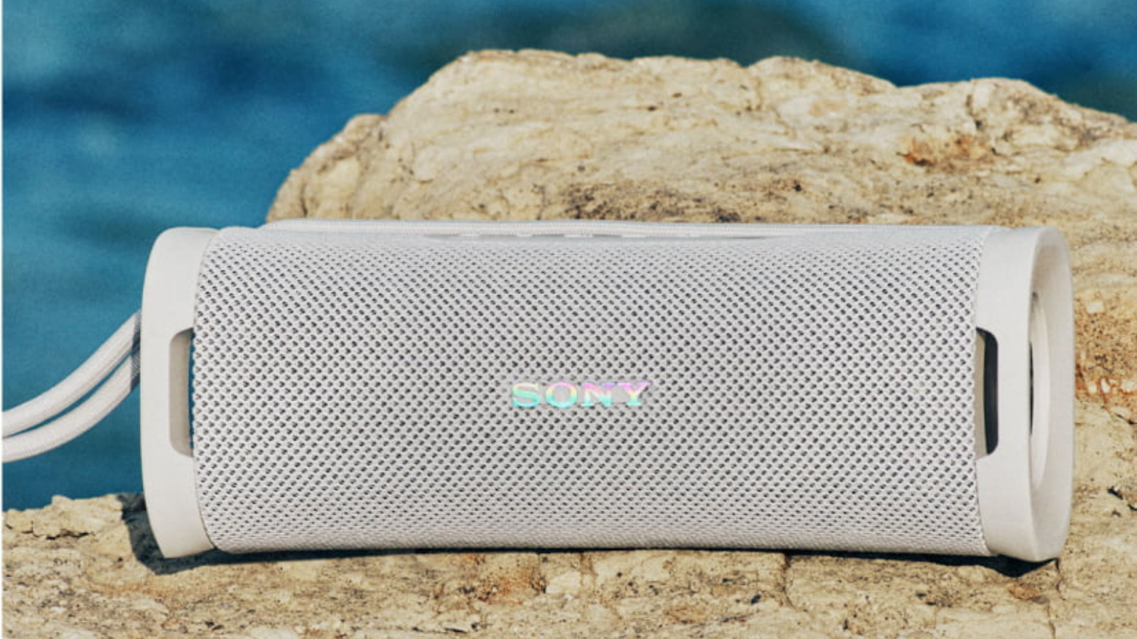 Sony ULT Field 1 speaker in off-white sitting on a rock