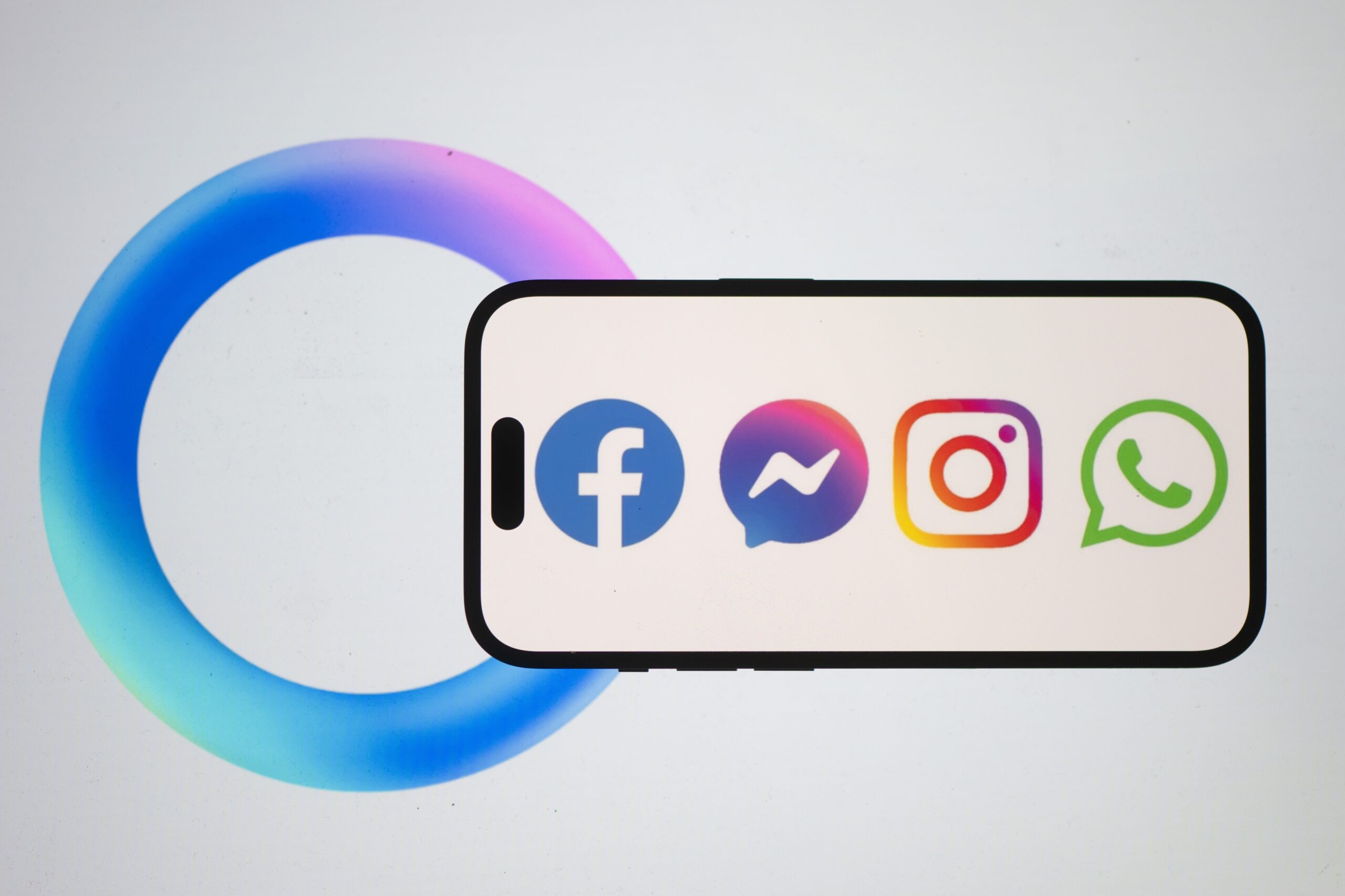 A phone showing the logos of Meta's products, including Facebook, Instagram, WhatsApp, and Messenger.