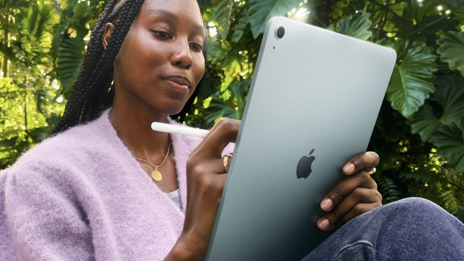 person sitting outside writing with apple pencil on blue ipad air