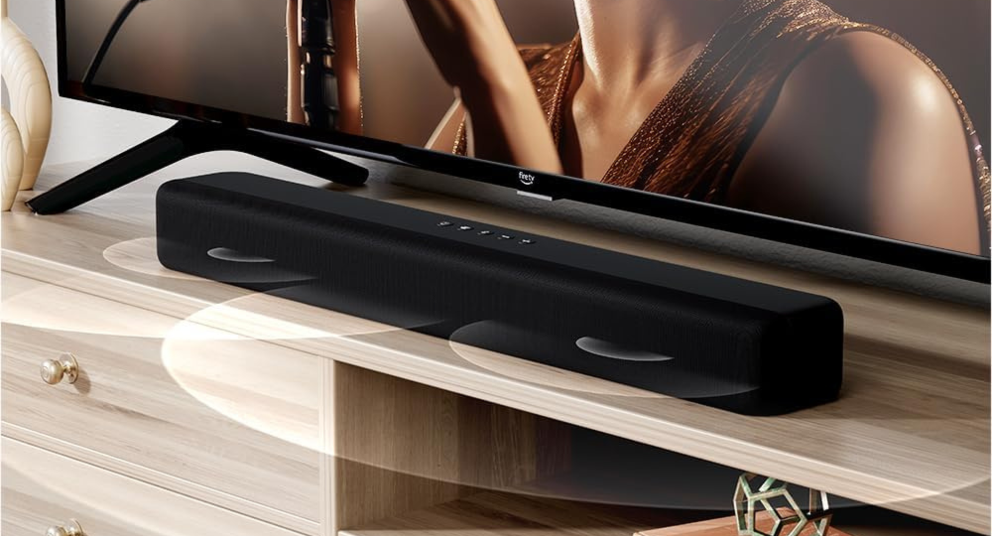 A sleek black soundbar rests on a light wood media console in front of a television.