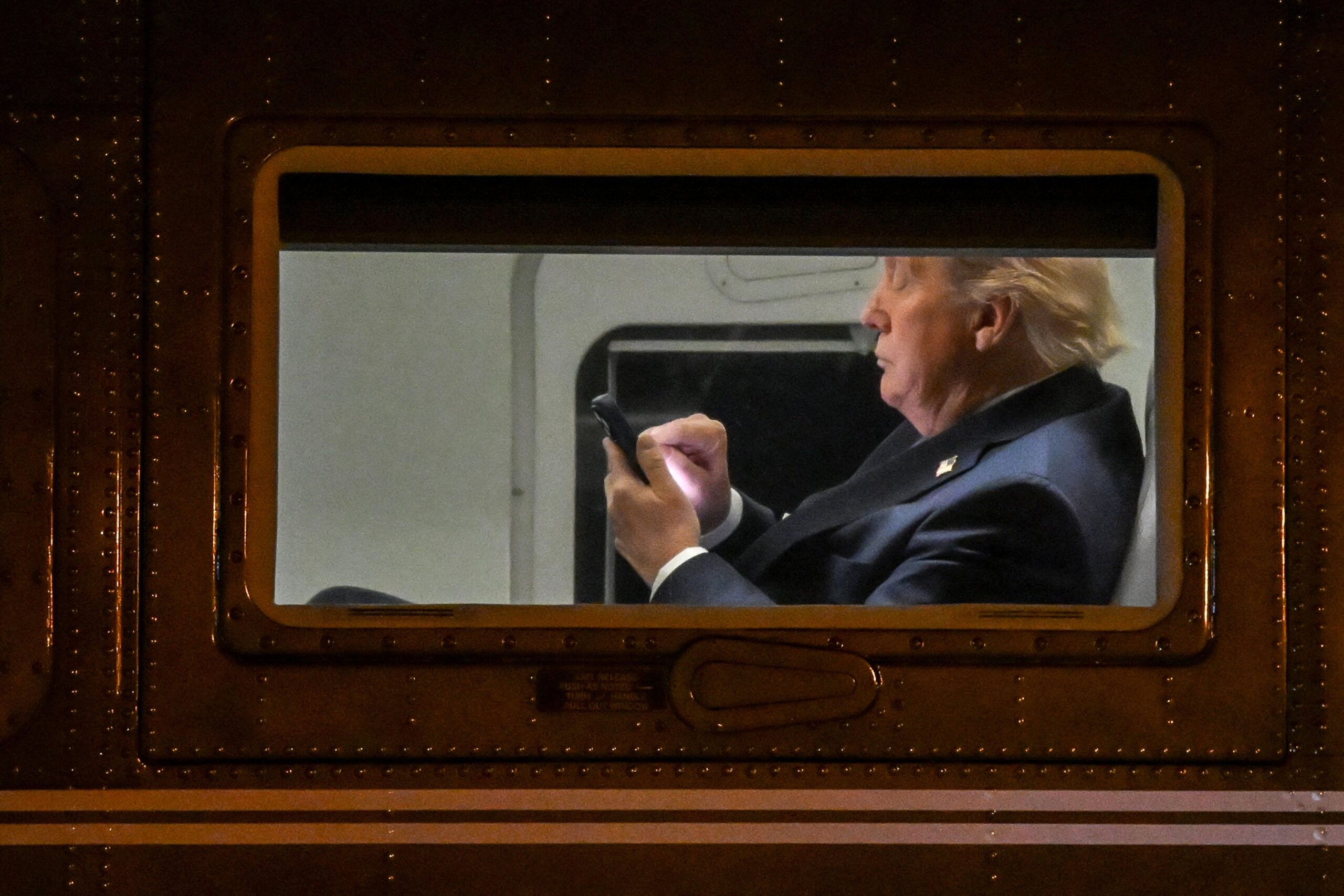 US President Donald Trump uses a cellphone aboard Marine One