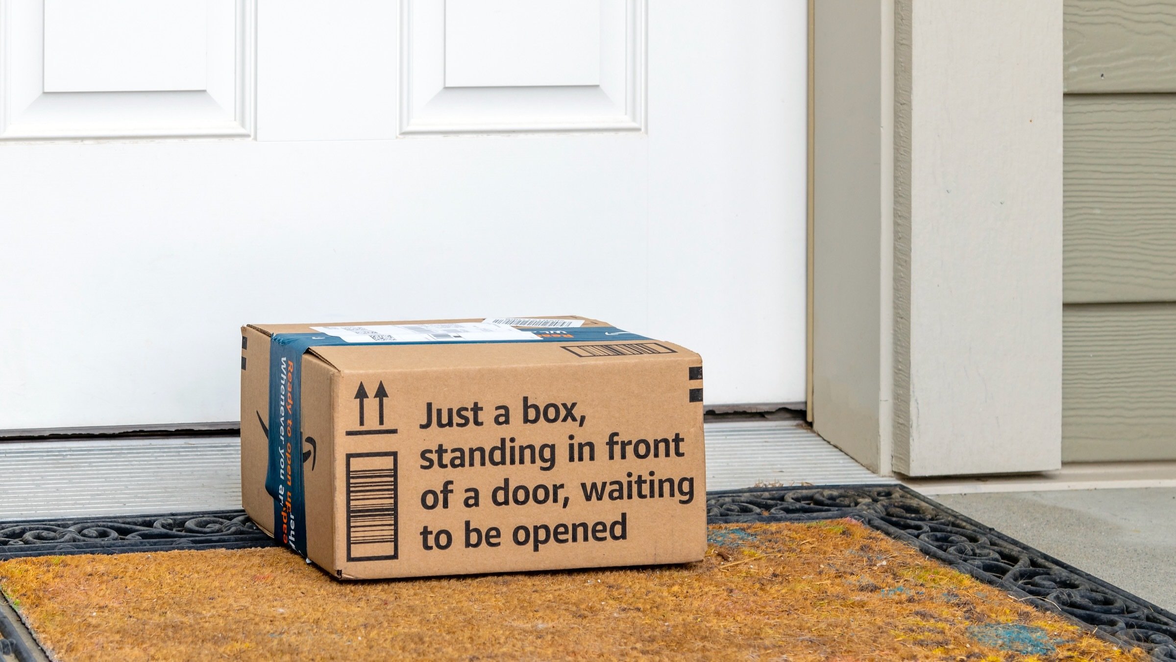 amazon prime box on doorstep with words 'just a box, on a doorstep, waiting to be opened' on cardboard