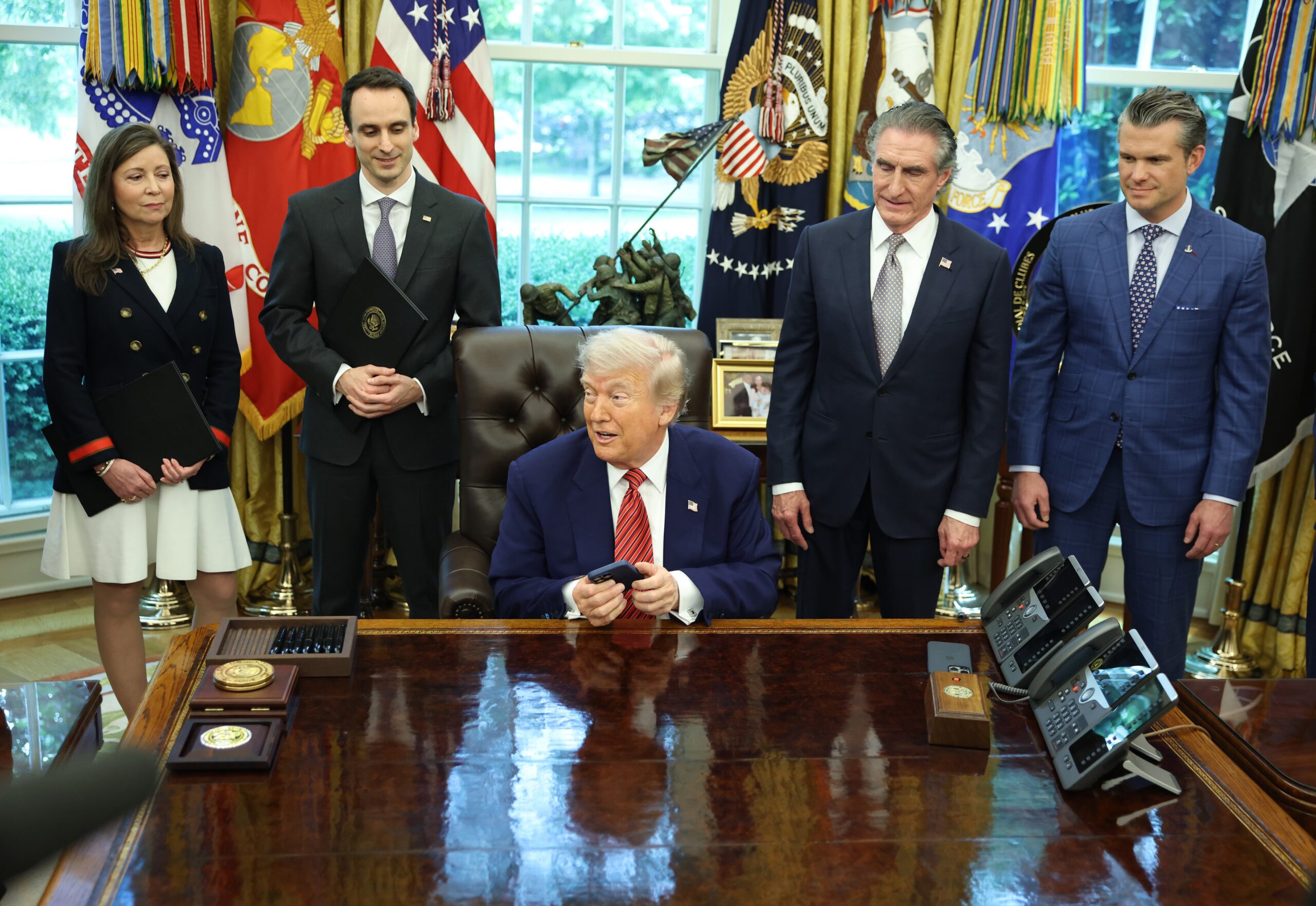 US President Donald Trump, center, holds an Apple Inc. iPhone
